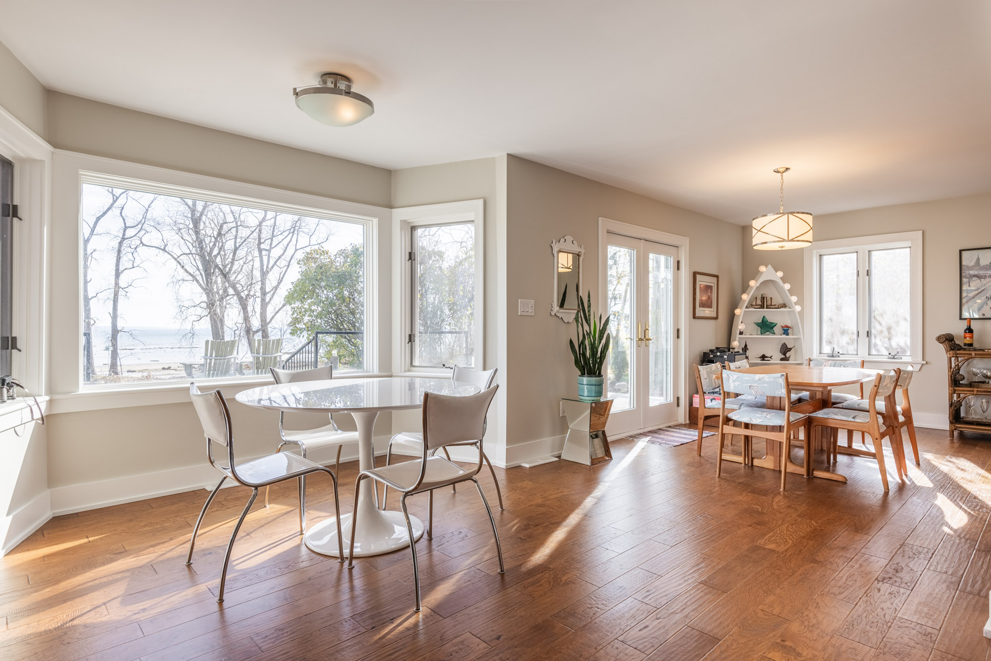 A small breakfast table with white chairs next to a wide bay window
