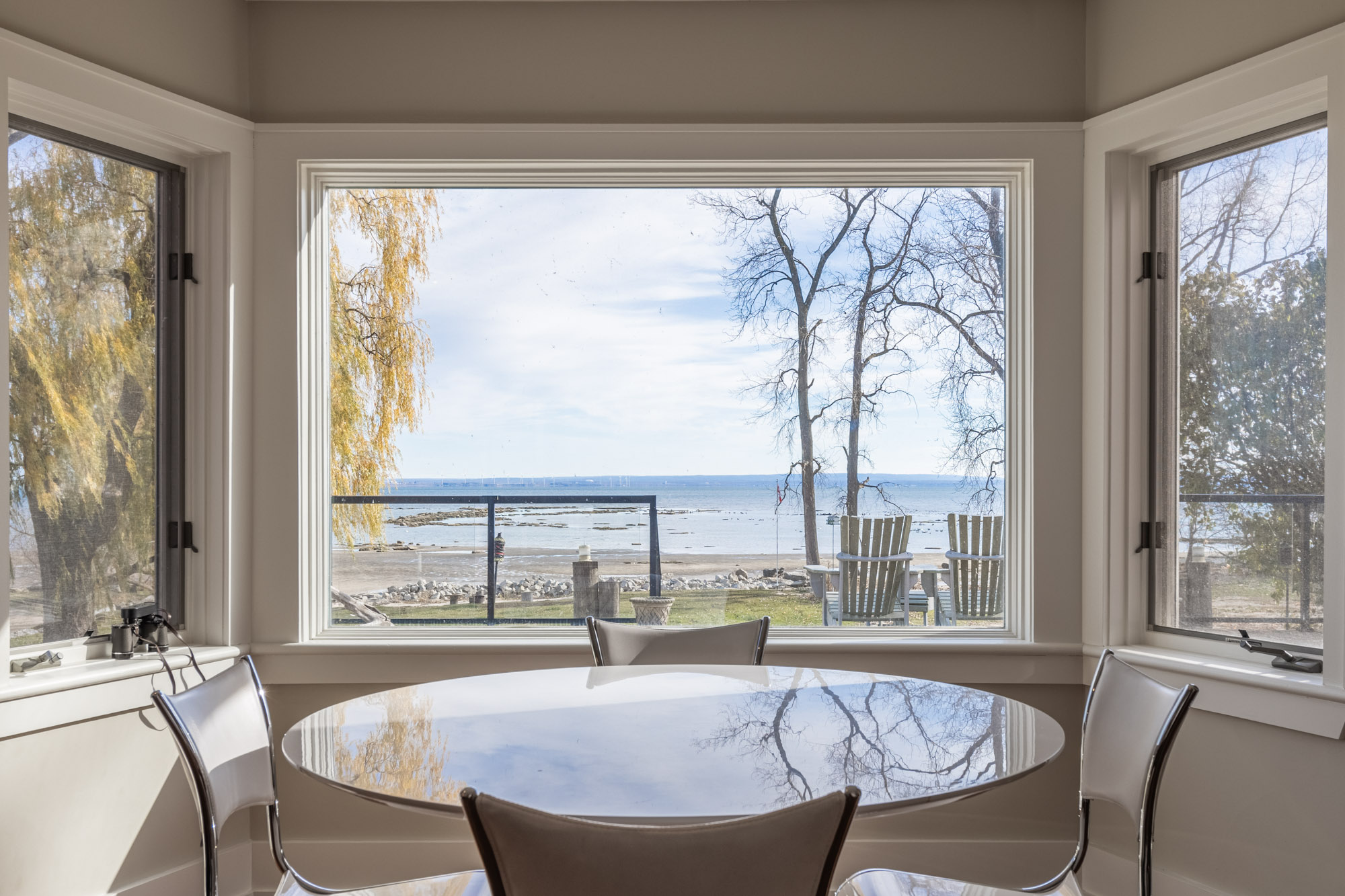 A small white table faces a large window that looks out onto the lake