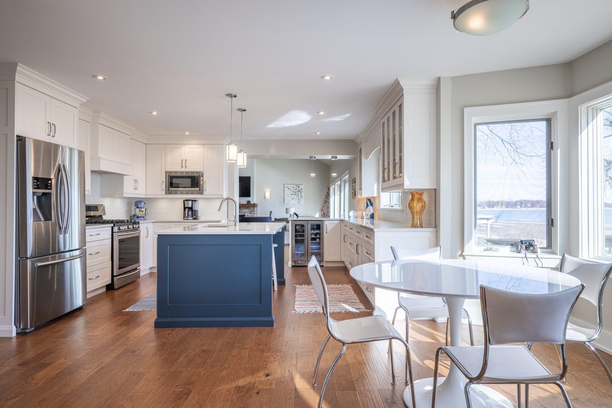 A stainless steel fridge, large blue kitchen island face the breakfast nook