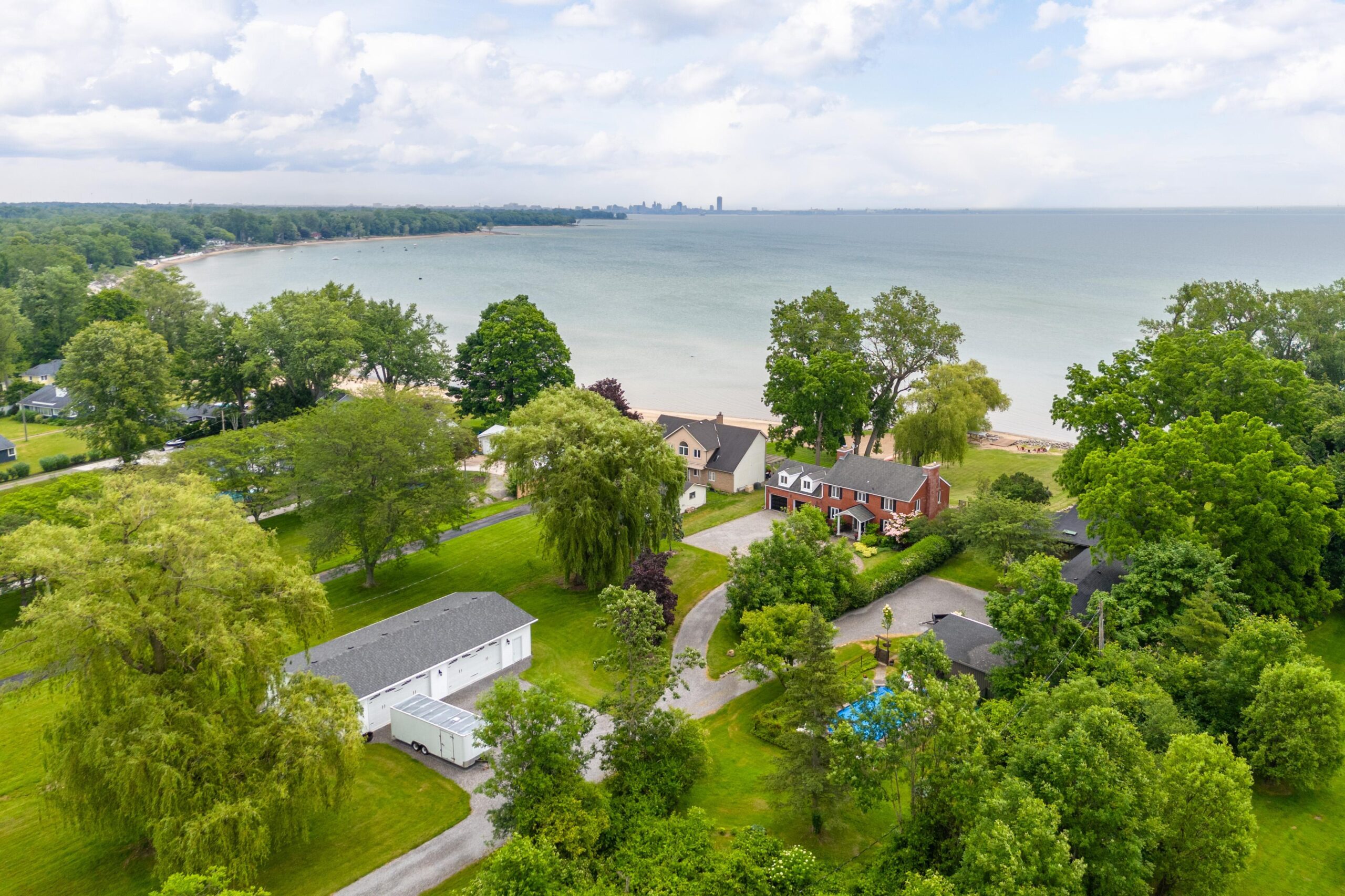 Aerial view of red brick house surrounded by trees and the lake in the distance
