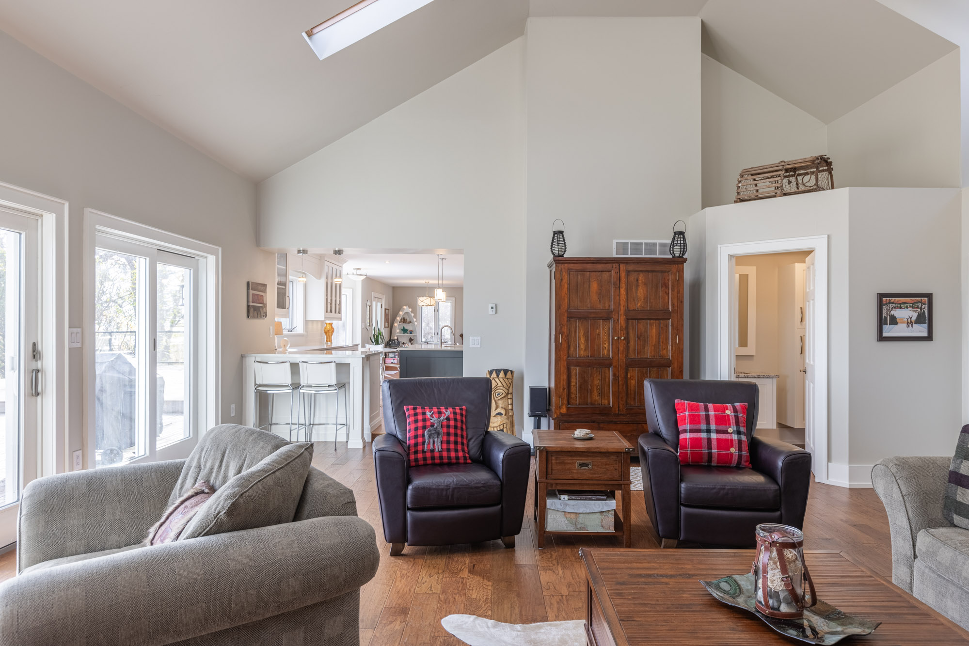 Two black leather chairs with red pillows with a brown cabinet behind