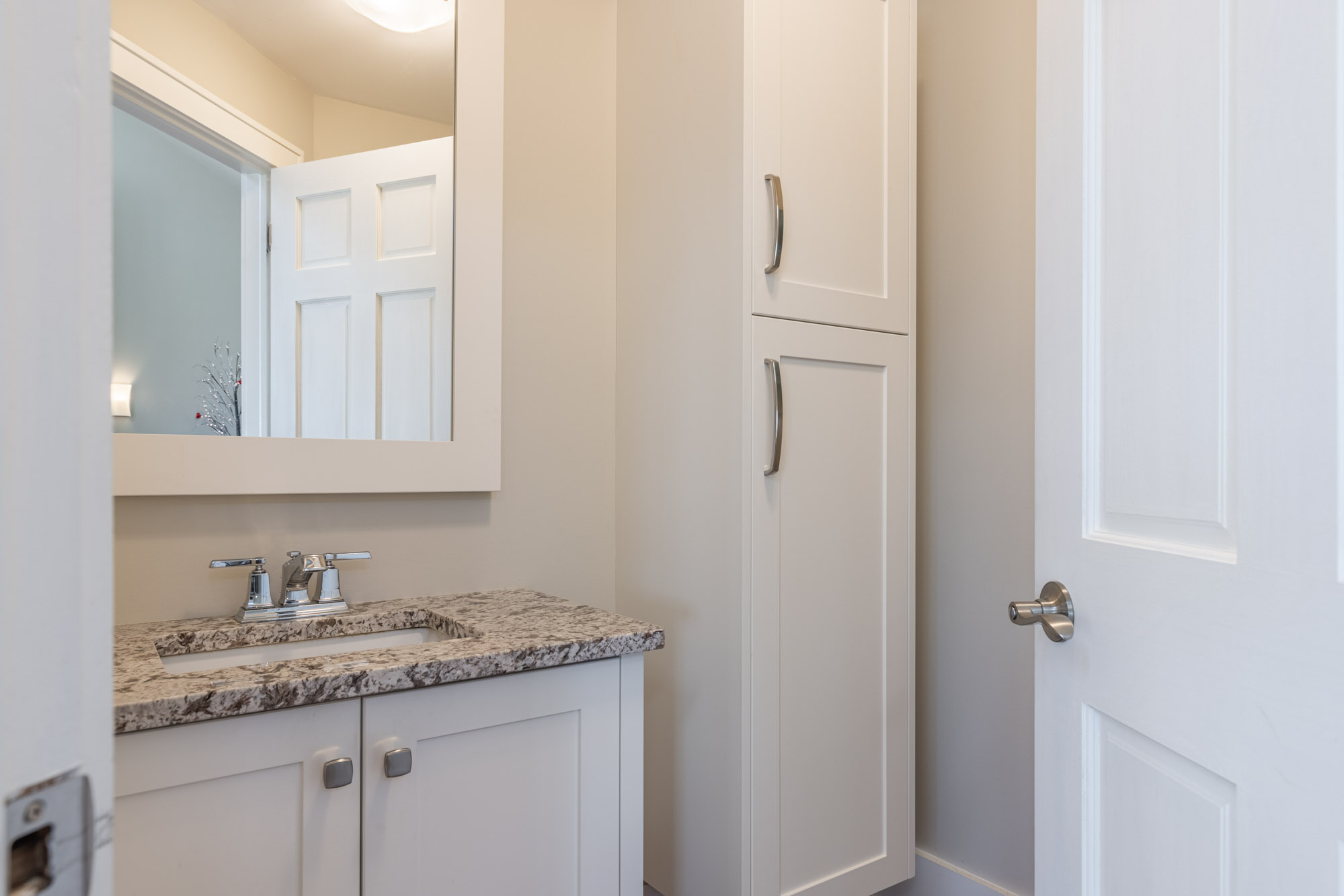 A white sink with marbled countertops with a mirror above
