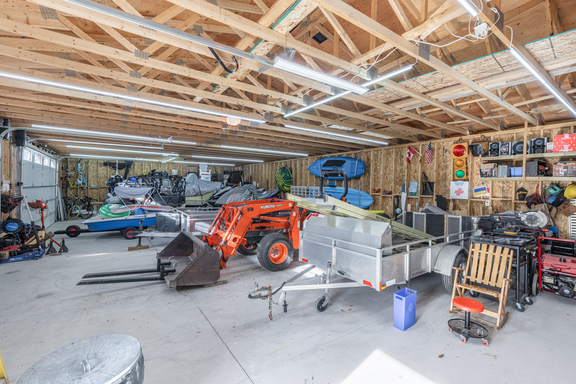 Different vehicles in a wide garage with a brown unfinished vaulted ceiling
