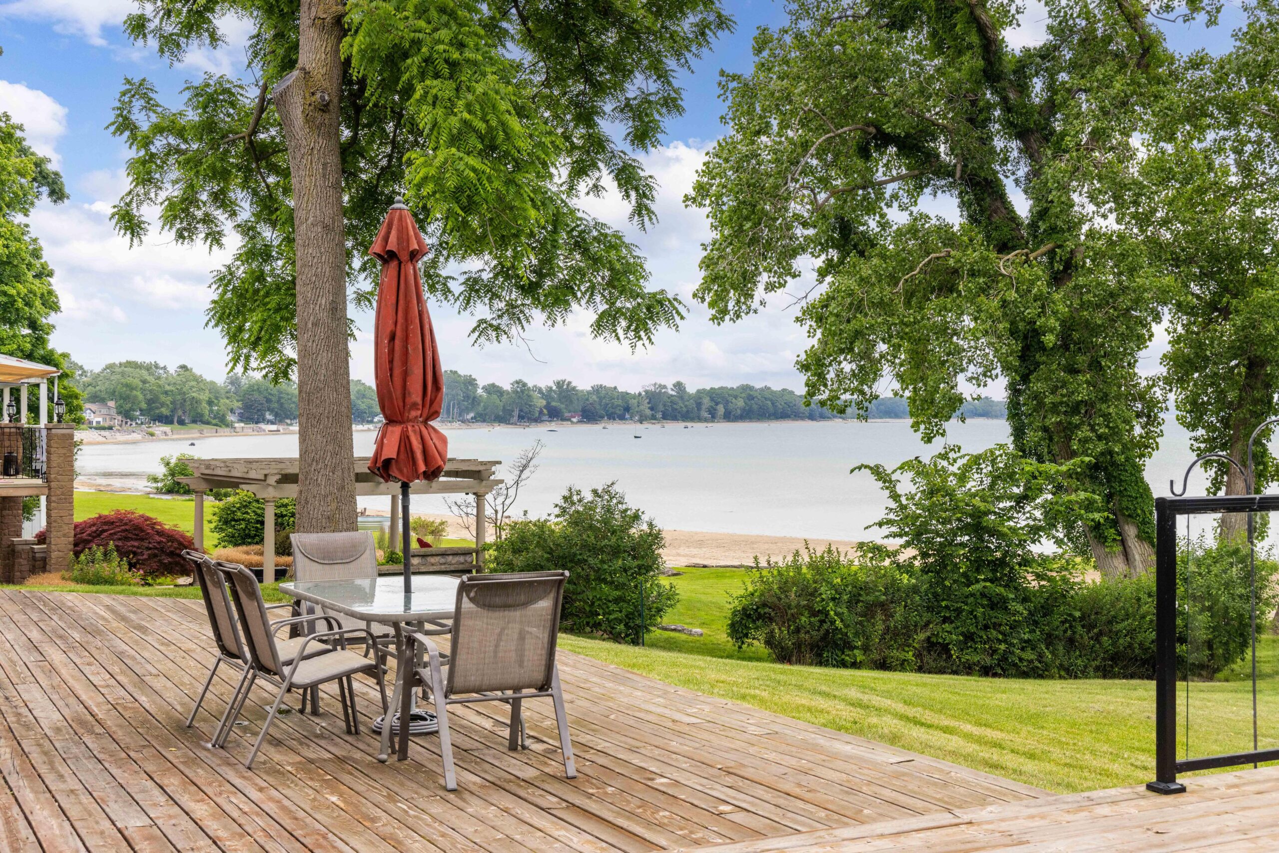 A small table with a closed red umbrella looks out to the lake