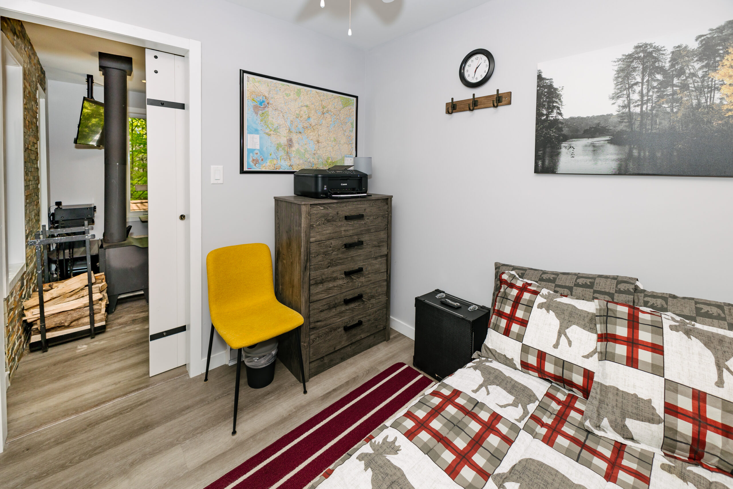 A red bed across from a grey dresser and yellow chair