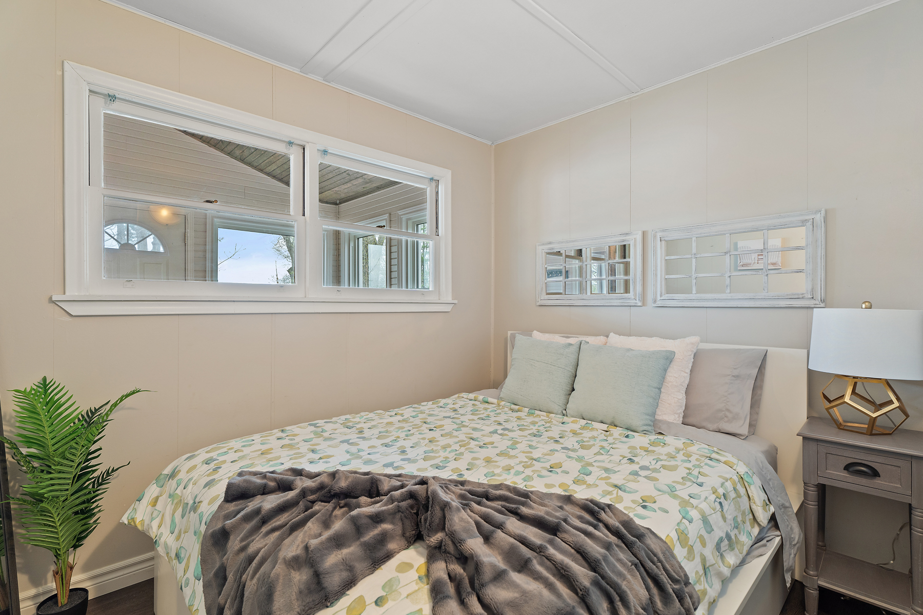 A small bedroom with a big bed and a big window.