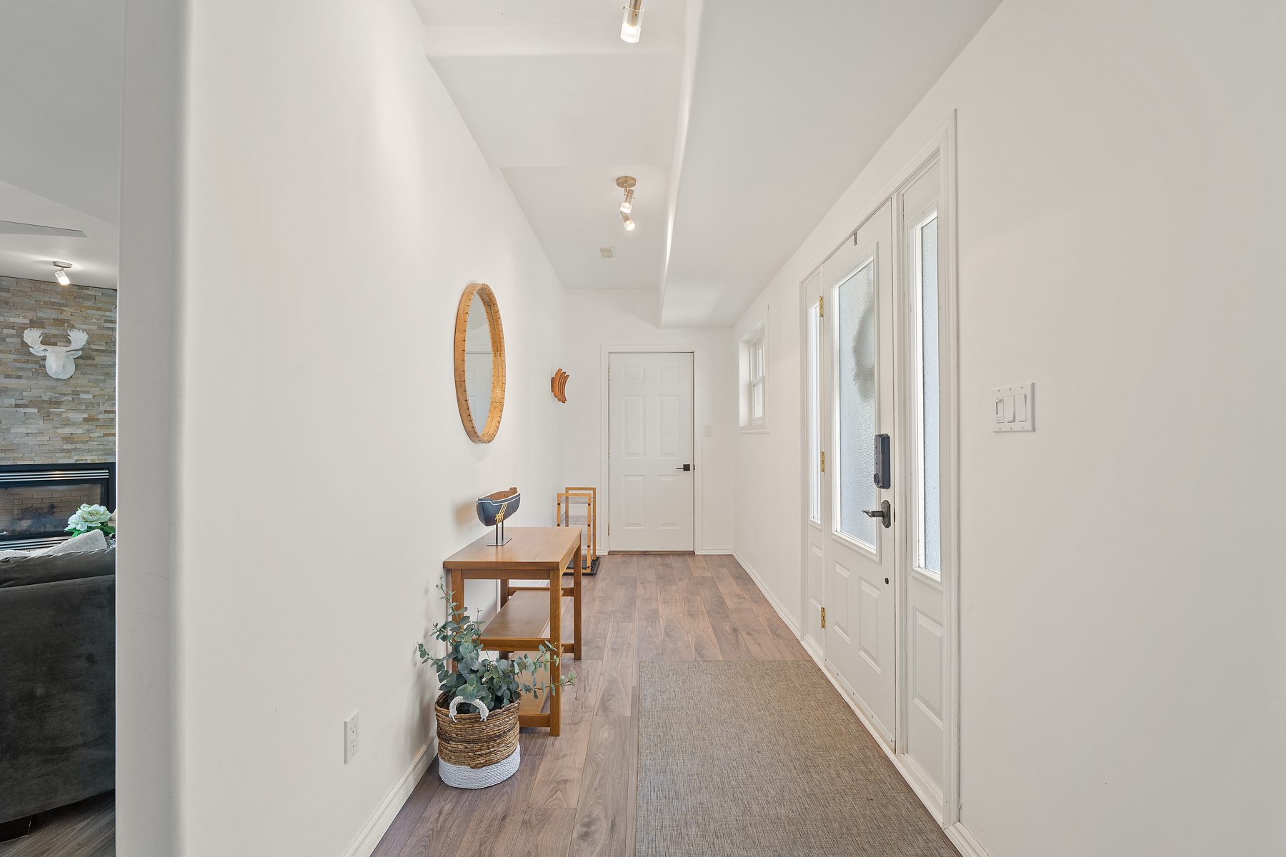 A bright white front hallway with wood floors and a little wood table across from the front door