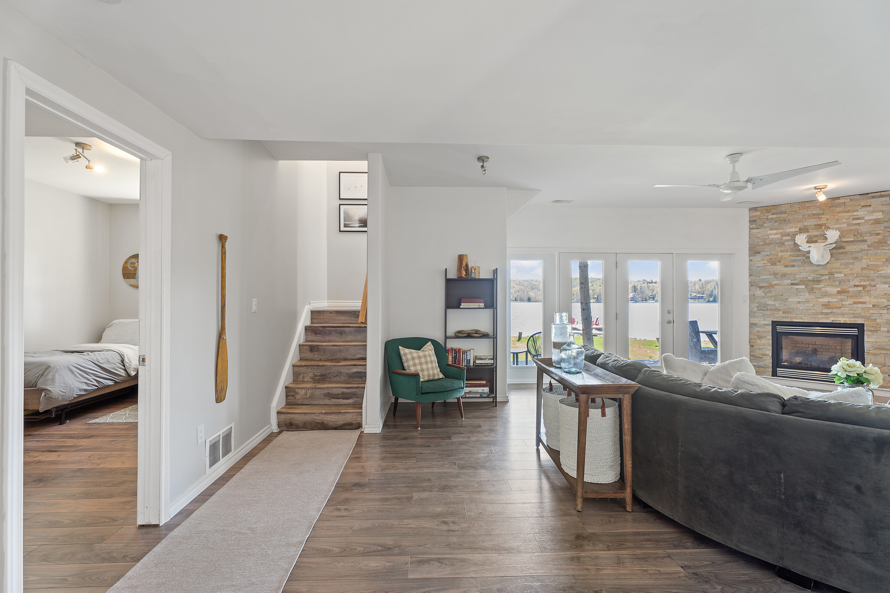 On the left, a set of stairs go up. To the right is a grey couch and a small side table