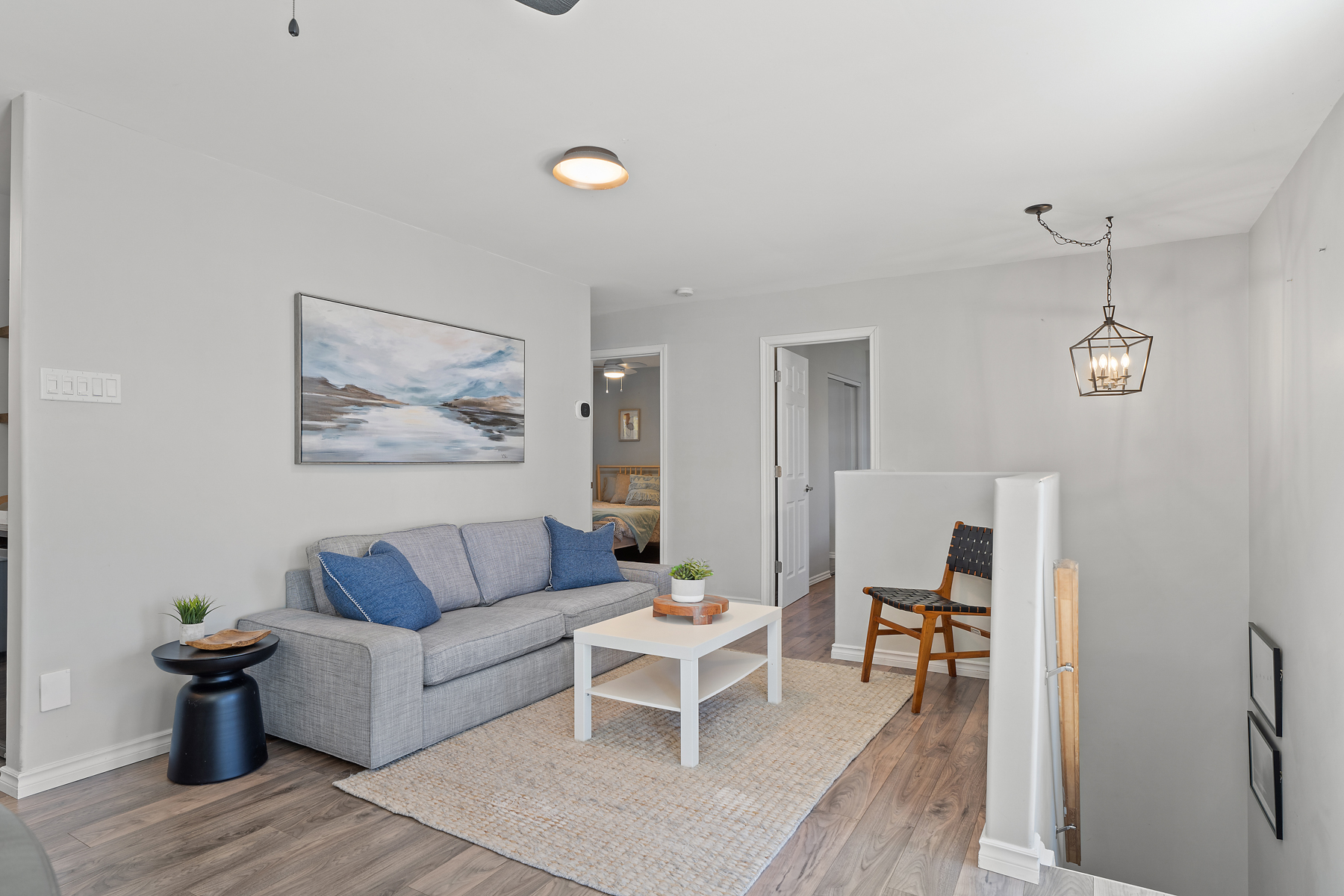 Secondary living area with a grey couch that faces the stairwell
