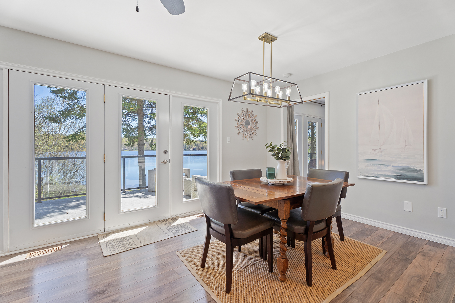 A small brown dining table with four chairs looks out onto the lake