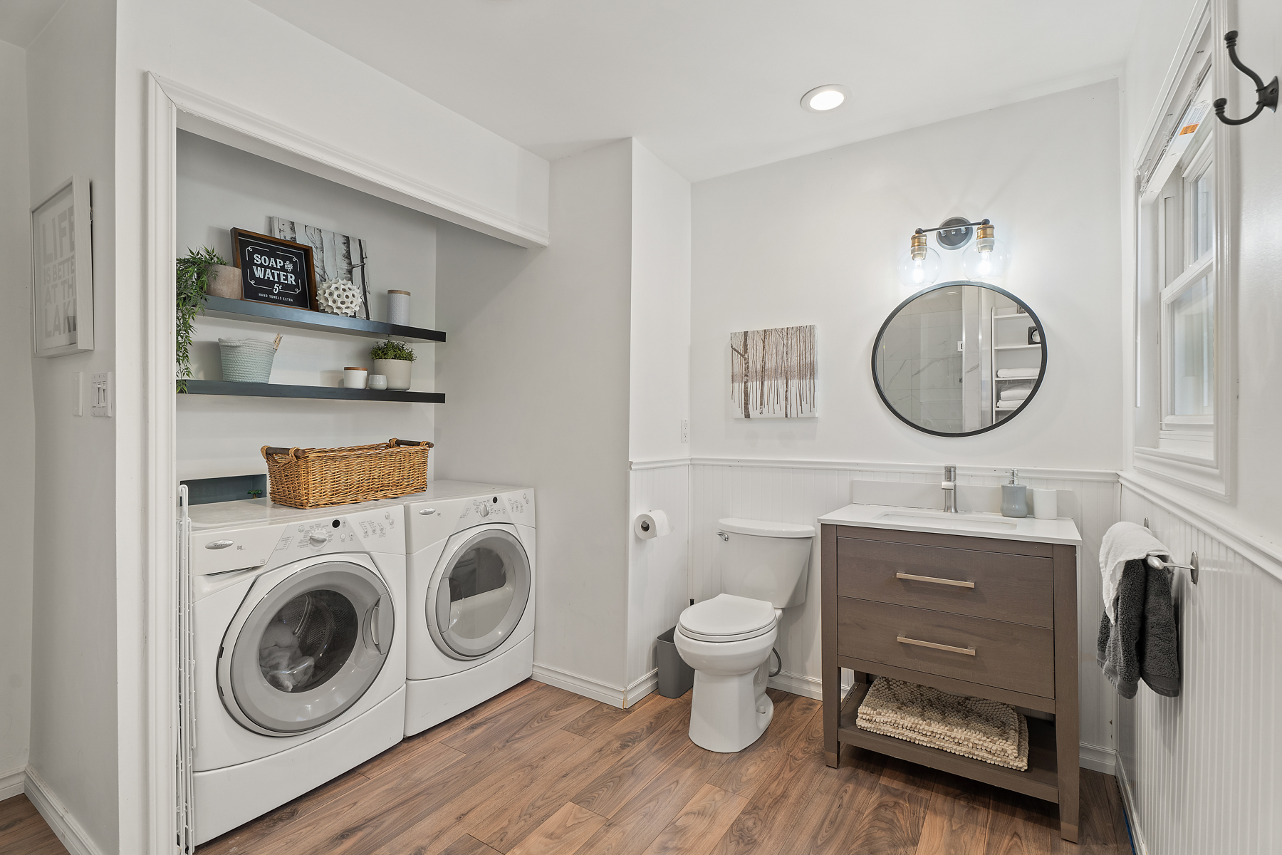 White laundry machines sit next to a toilet and brown vanity