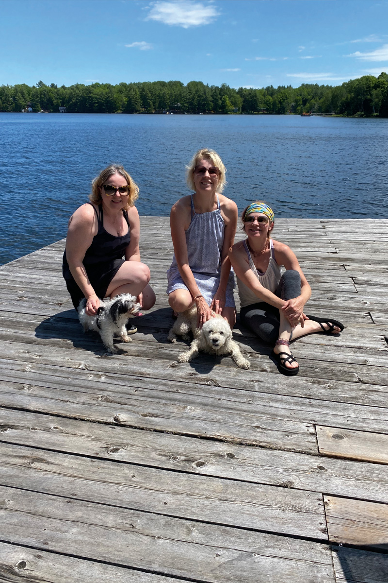 a photo of three women sitting on a dock