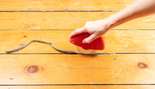 Someone fixing a gap in flooring with a foam strip