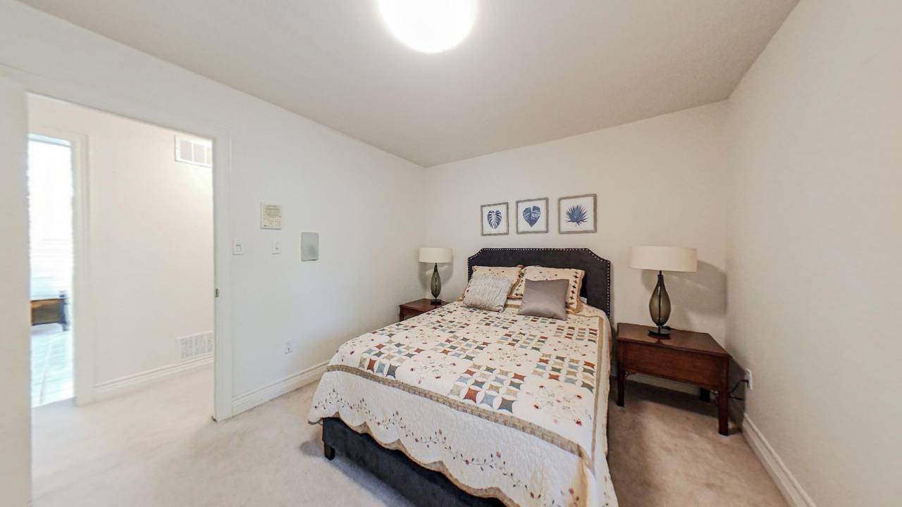 A patterned bed with three photos hanging above the headboard in a white room