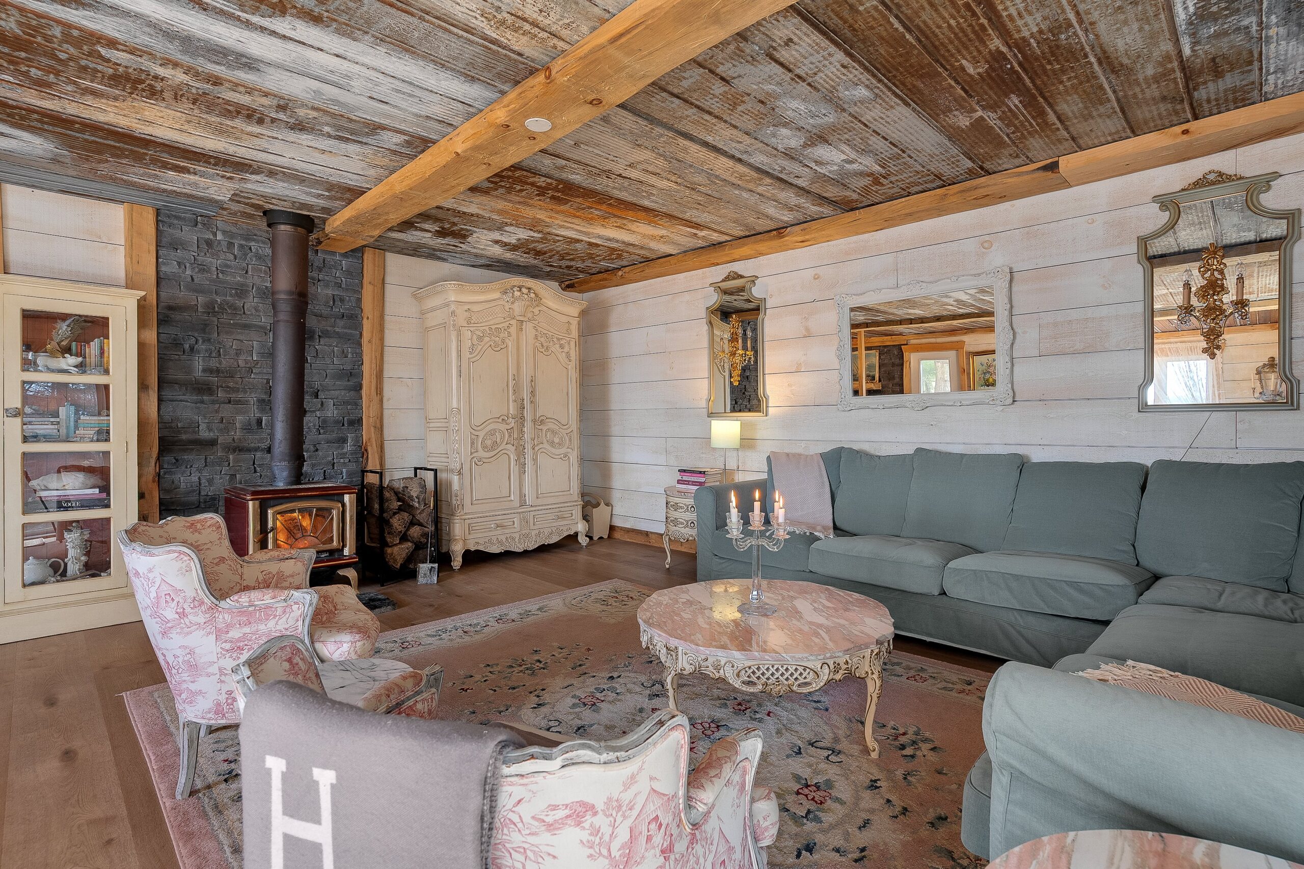 A turquoise couch on a pink rug faces a white coffee table and pink chairs
