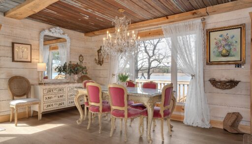 A white table with pink dining chairs next to a wide window