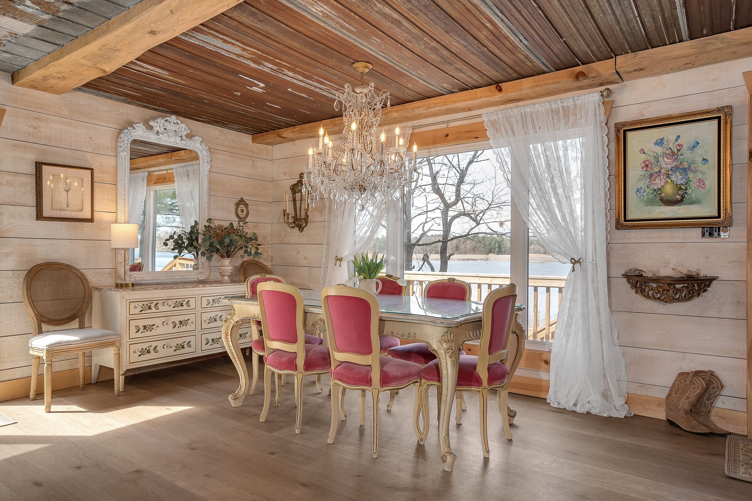 A white table with pink dining chairs next to a wide window