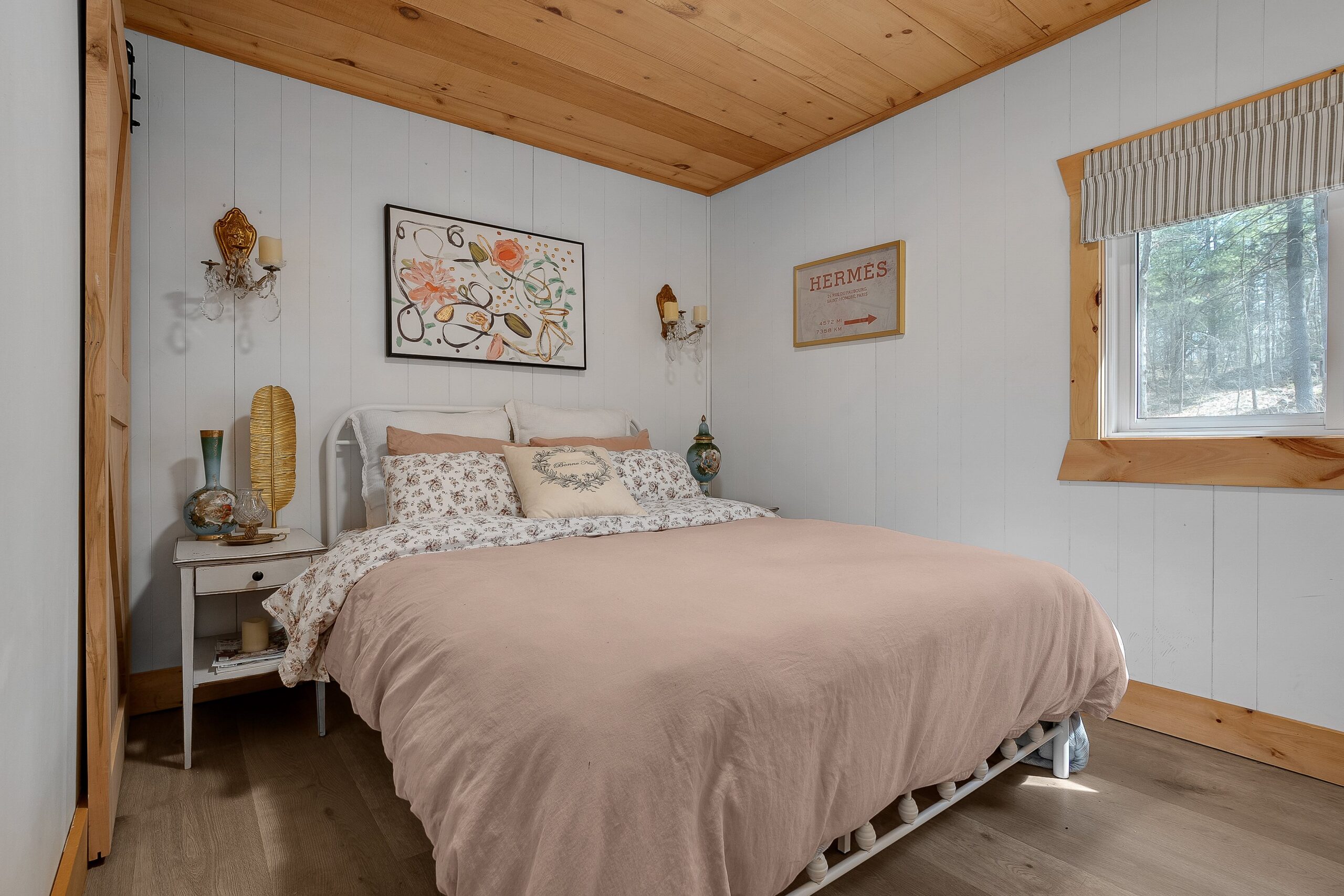 A bed with a pink bedspread in a white room