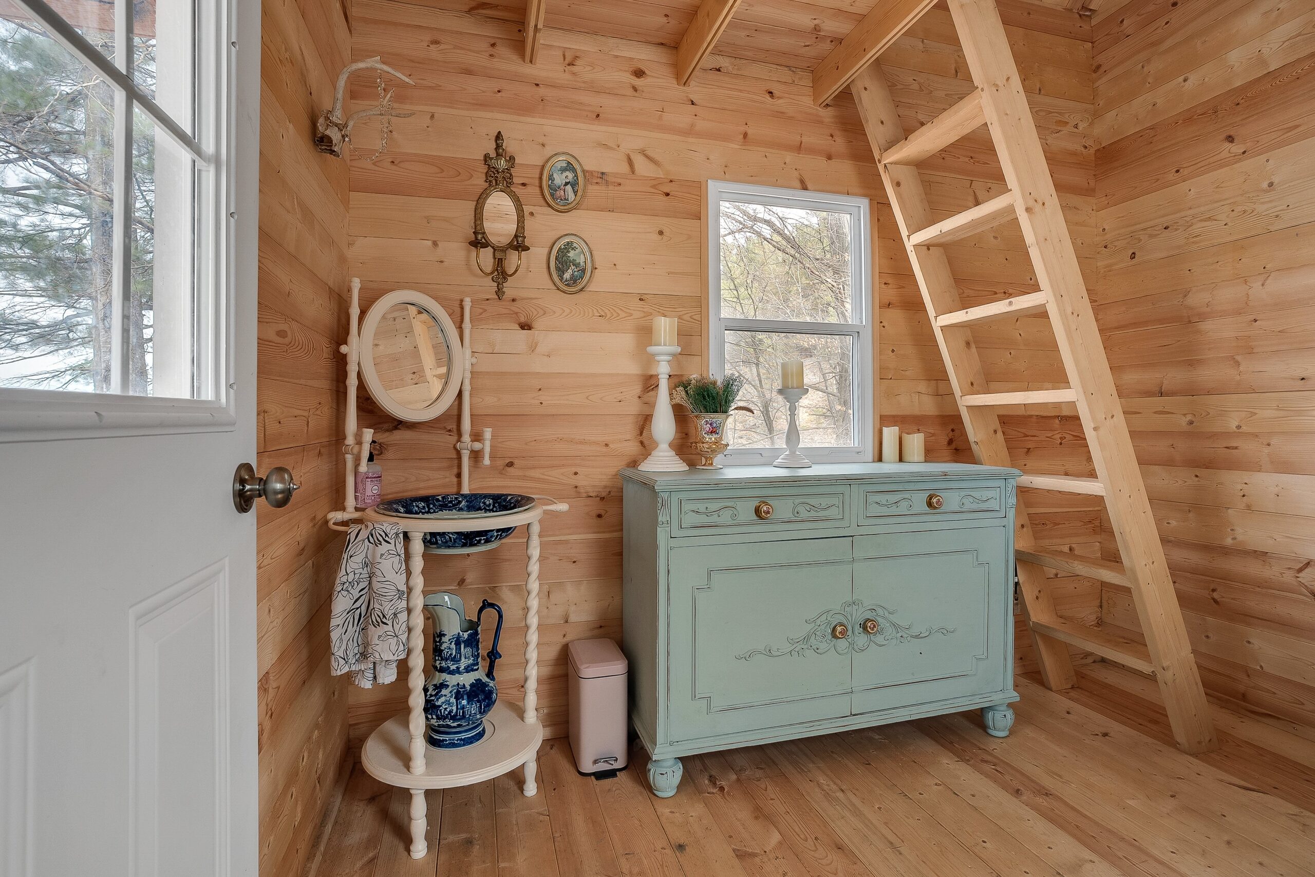 A turquoise cabinet next to a small white table in a wood room
