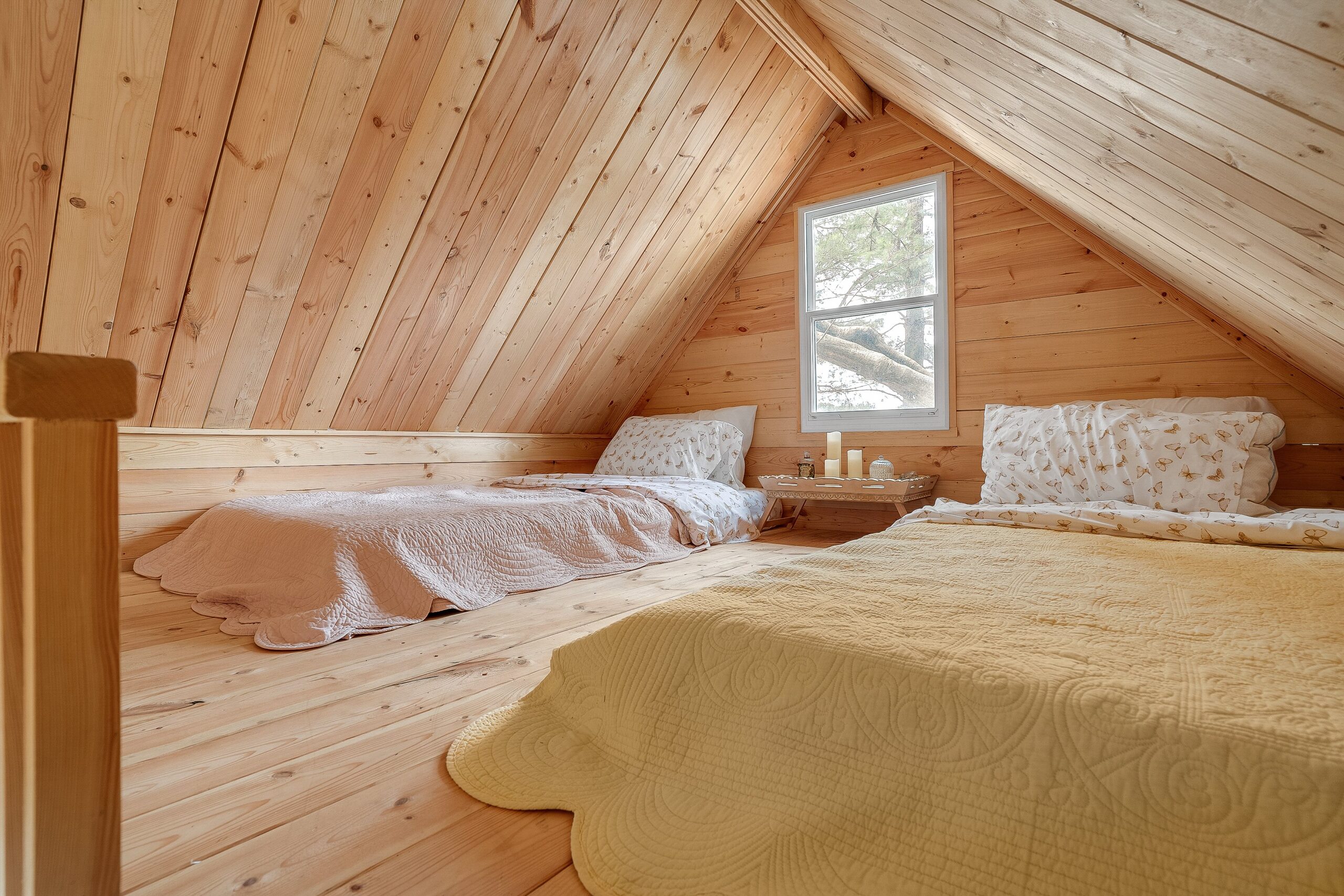 An A-frame shaped room with two beds on the floor