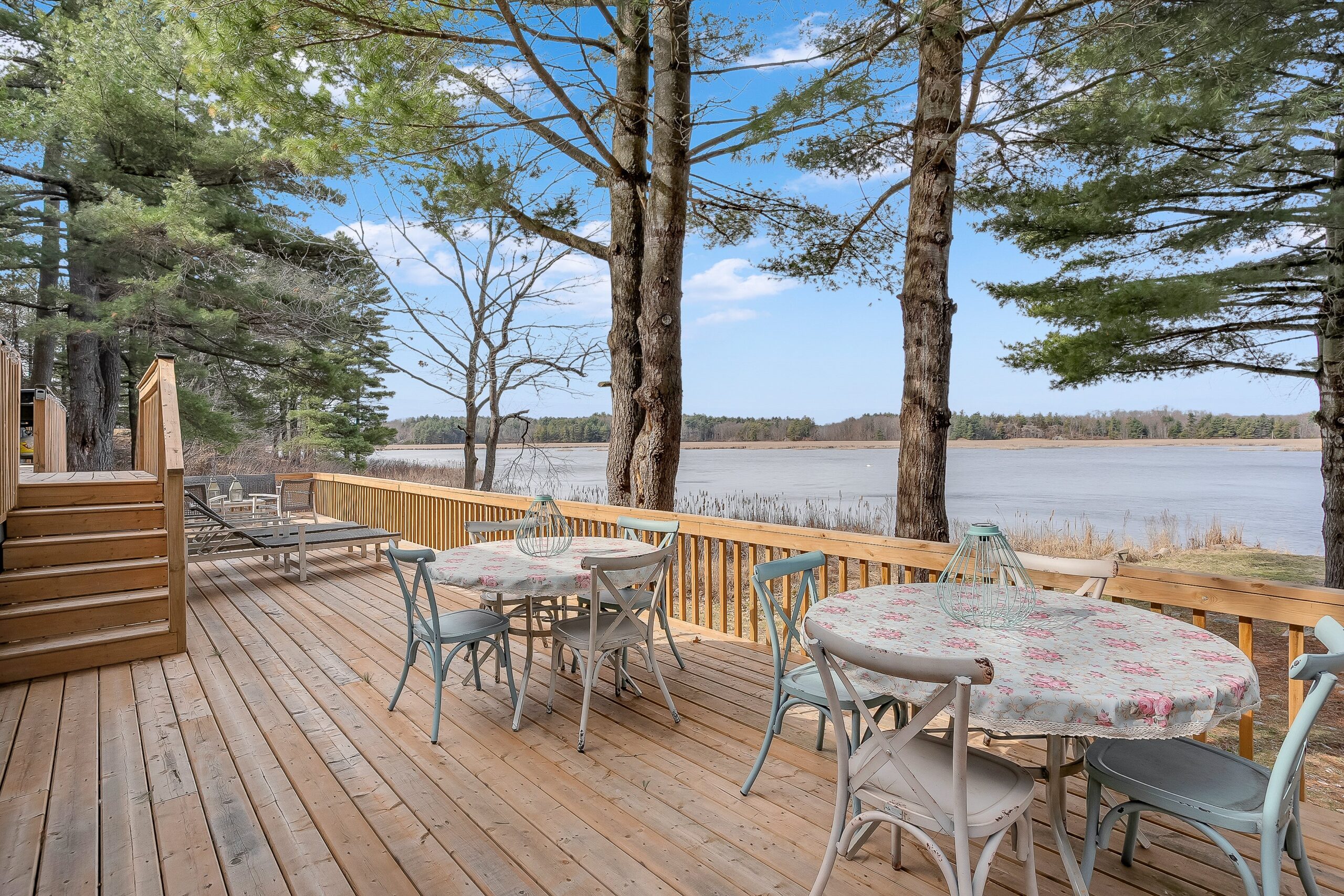 Two round outdoor dining tables on teh deck face the river