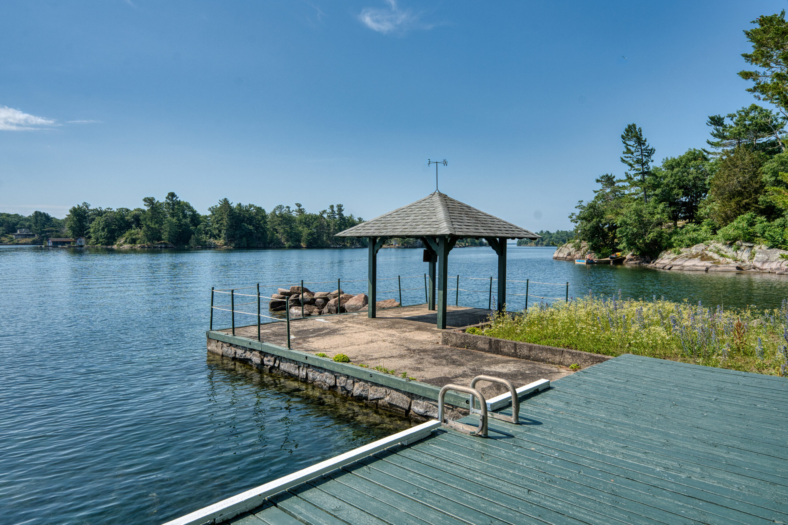 A green dock leads to a stone area with a gazebo