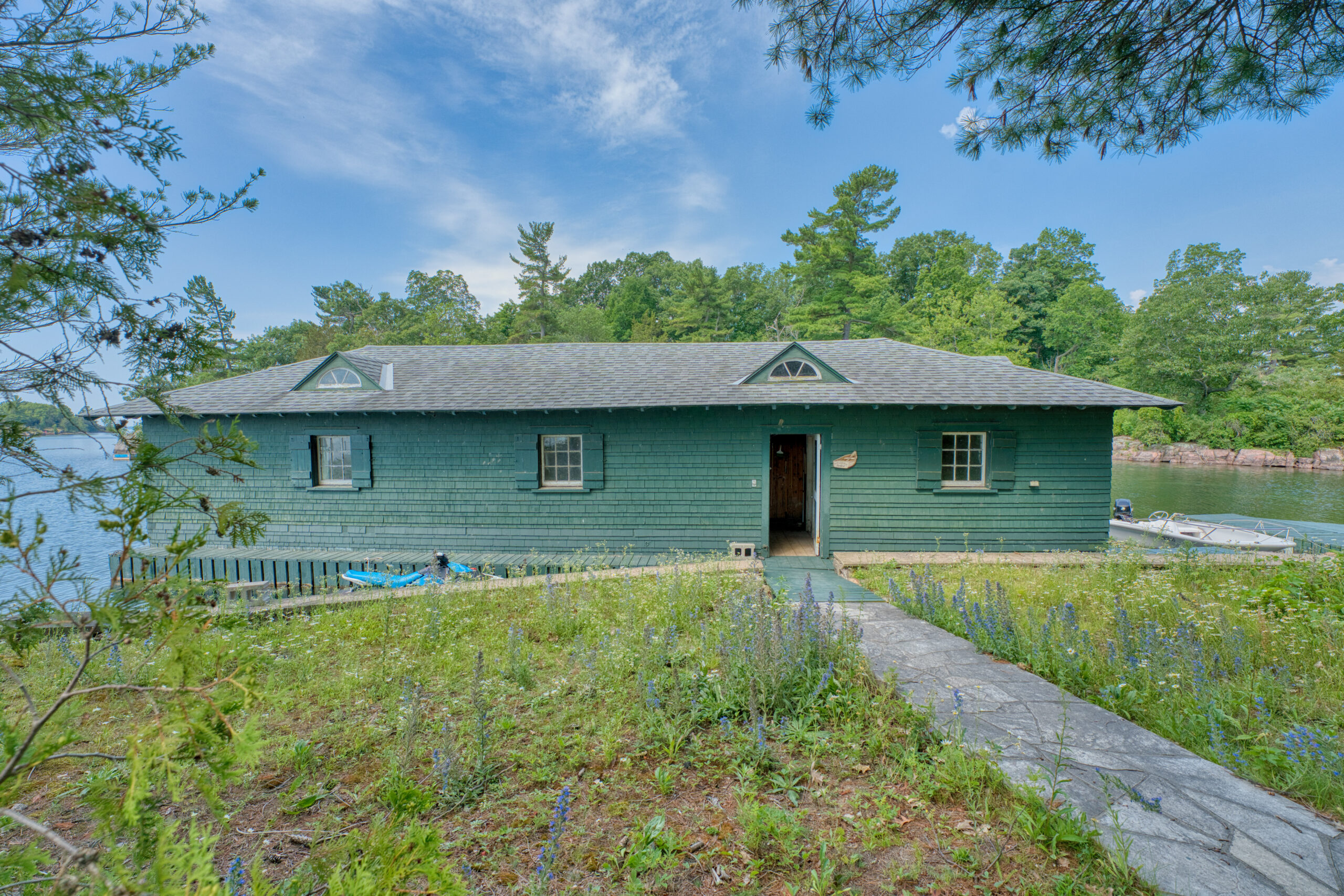 A path leads to a long green boathouse