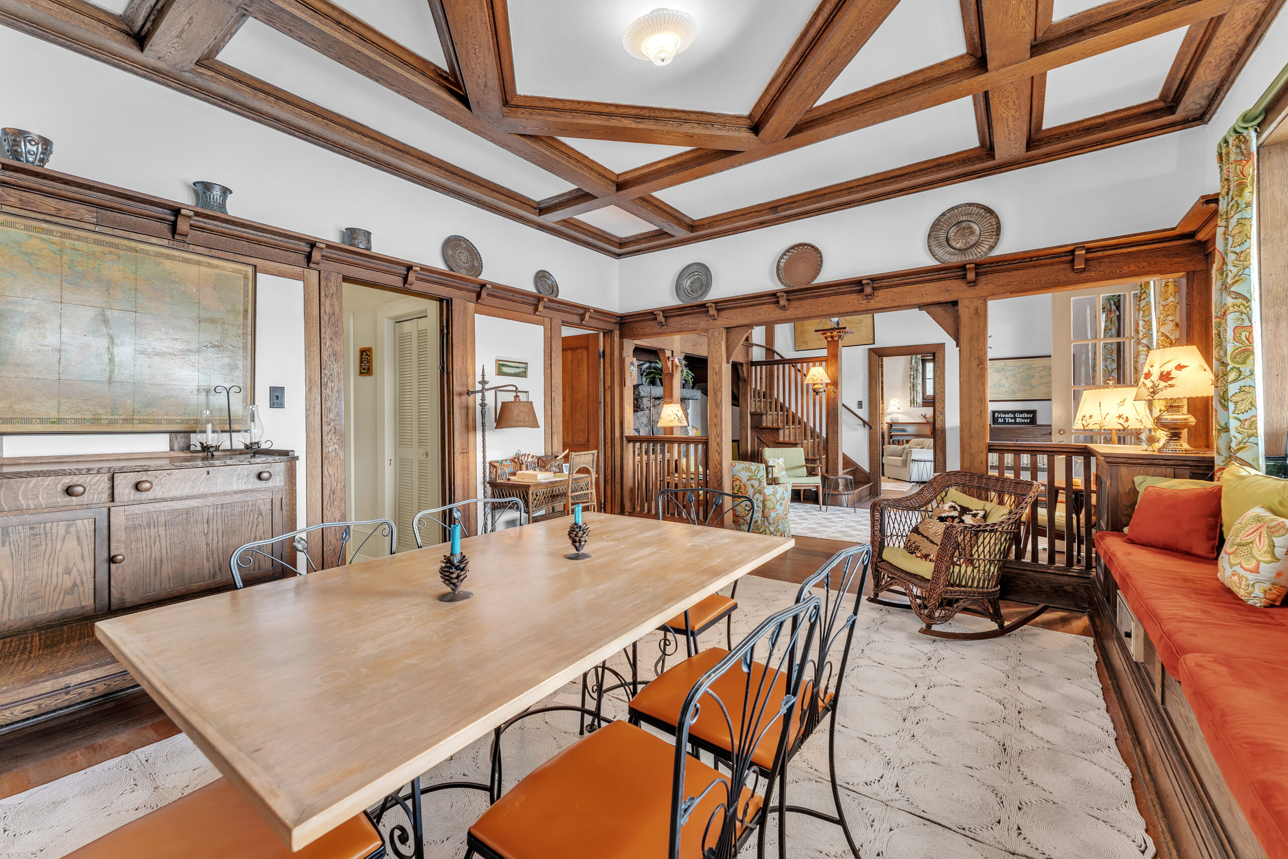 A wood dining table with orange chairs faces the foyer