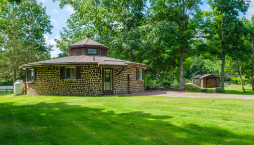 A round stone cottage on a bright grassy lawn