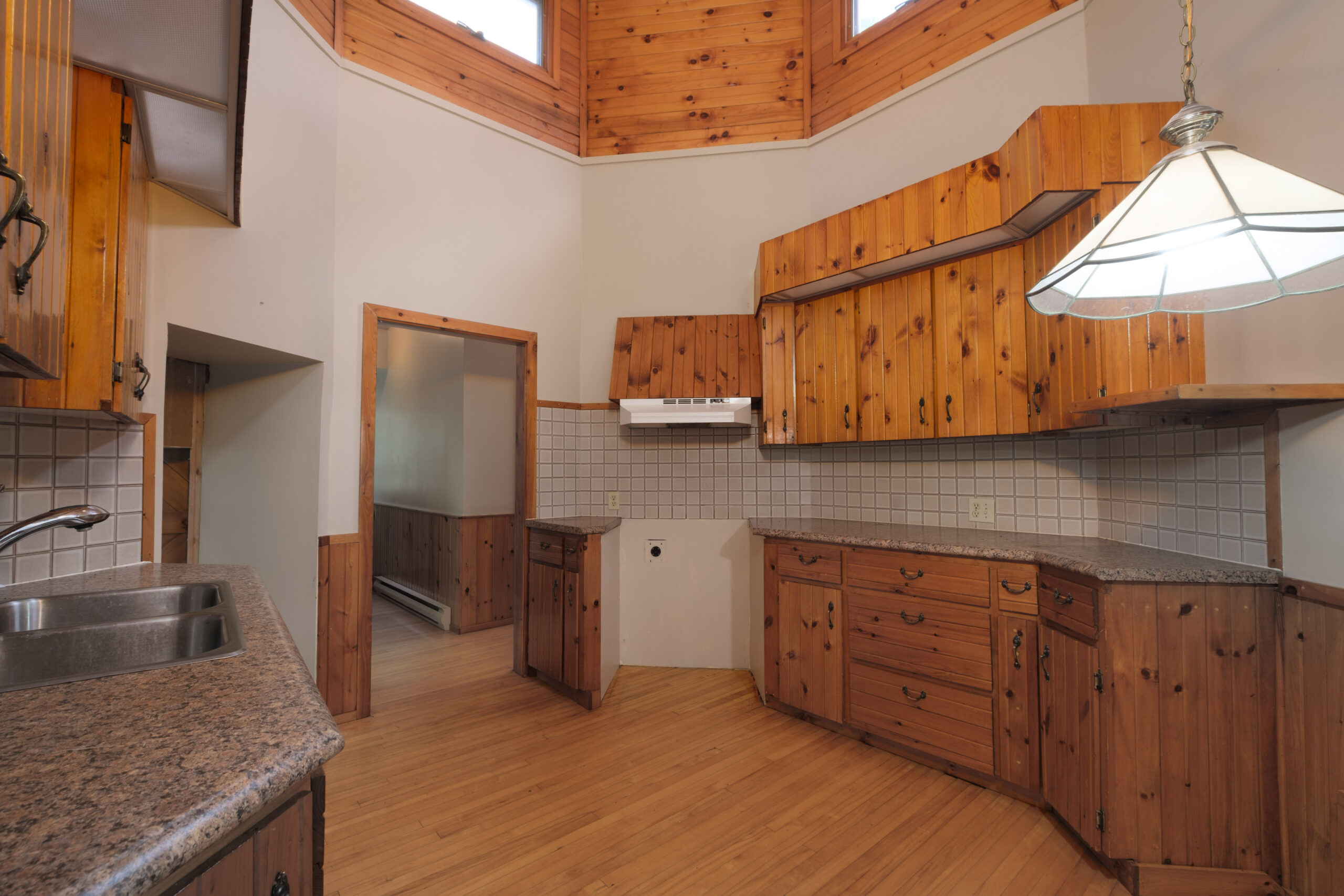 A rounded kitchen with wood floors and cabinets