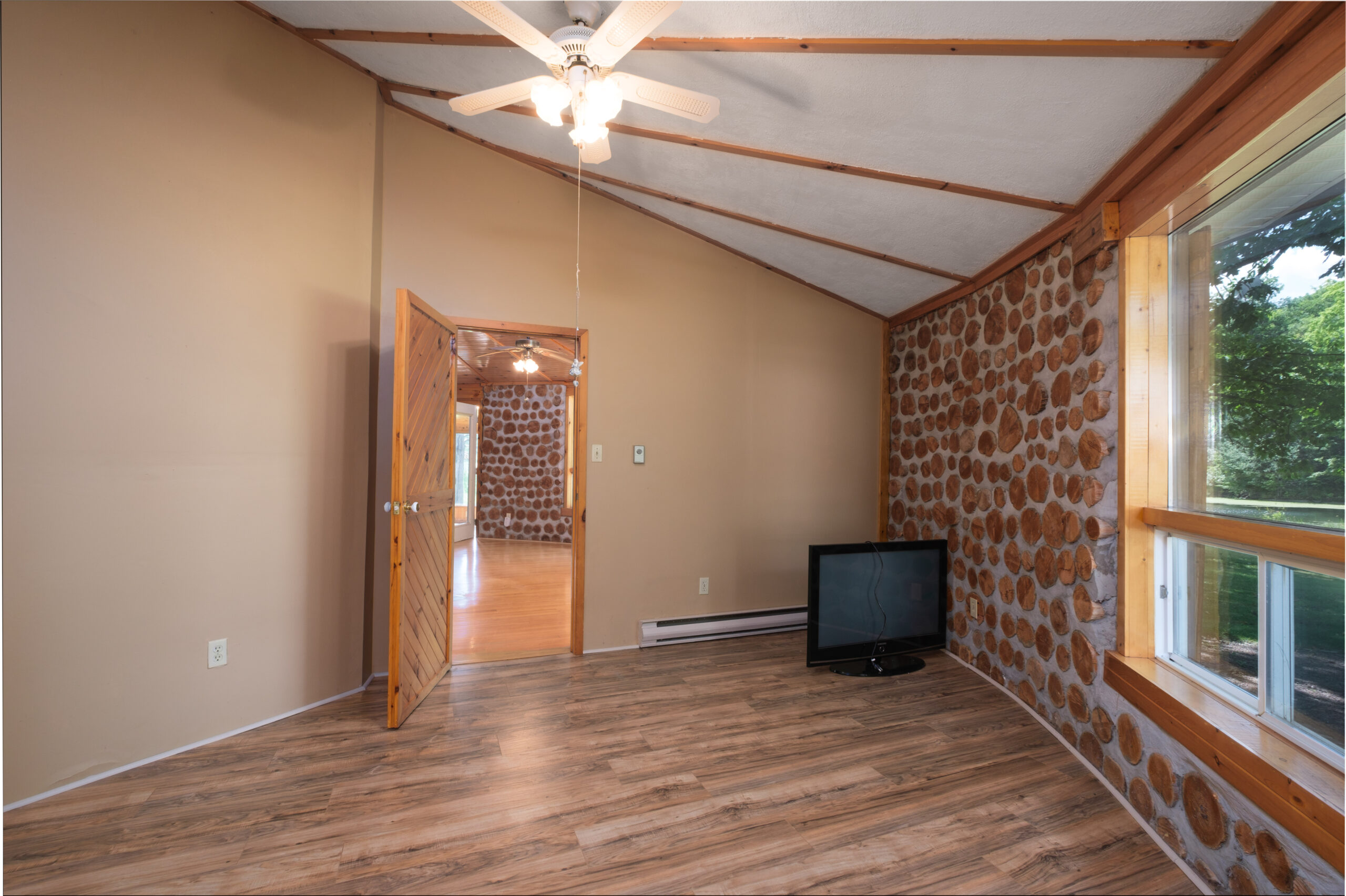 A rounded room with wood floors and a stone wall