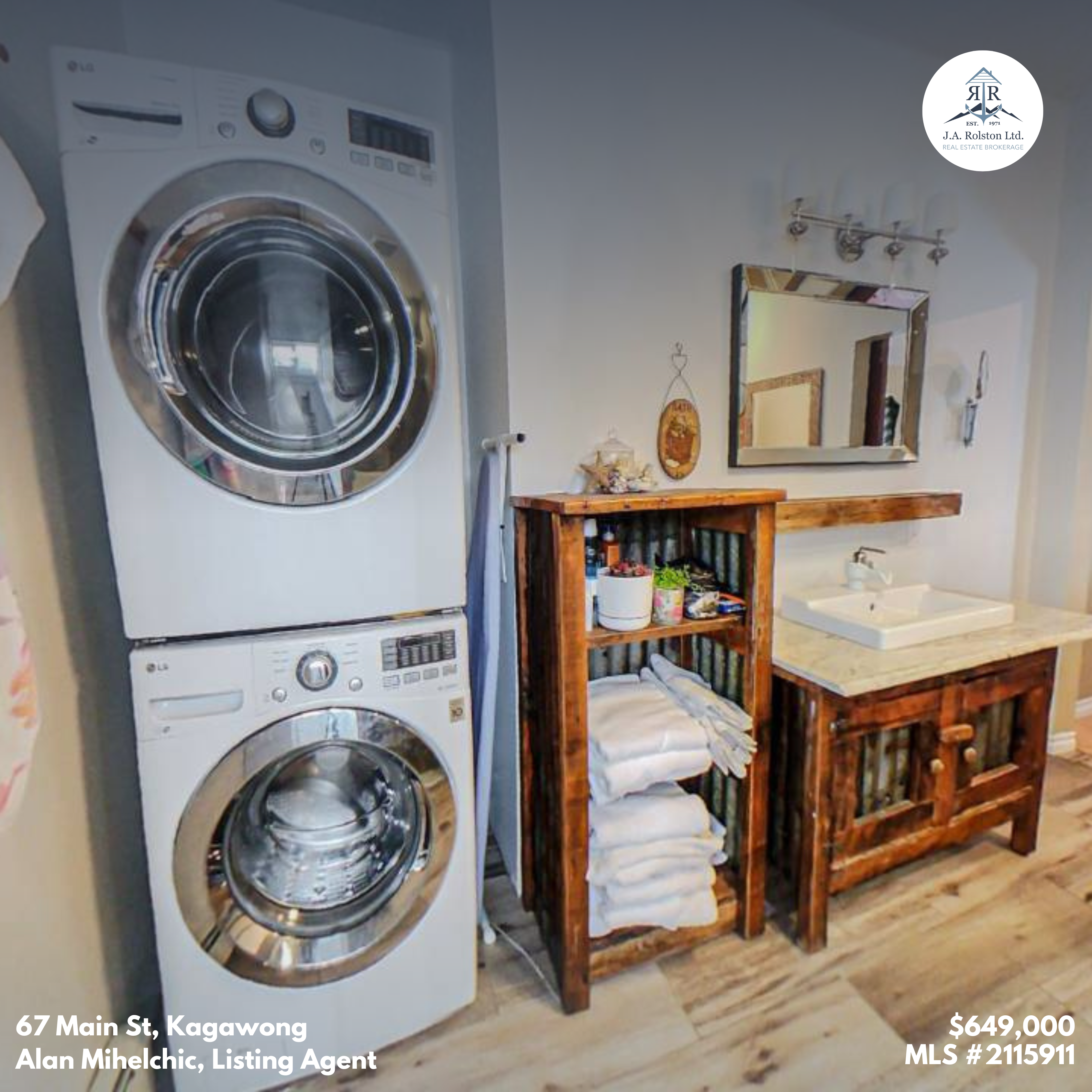 Stacked white laundry machines next to a wood vanity with a mirror above
