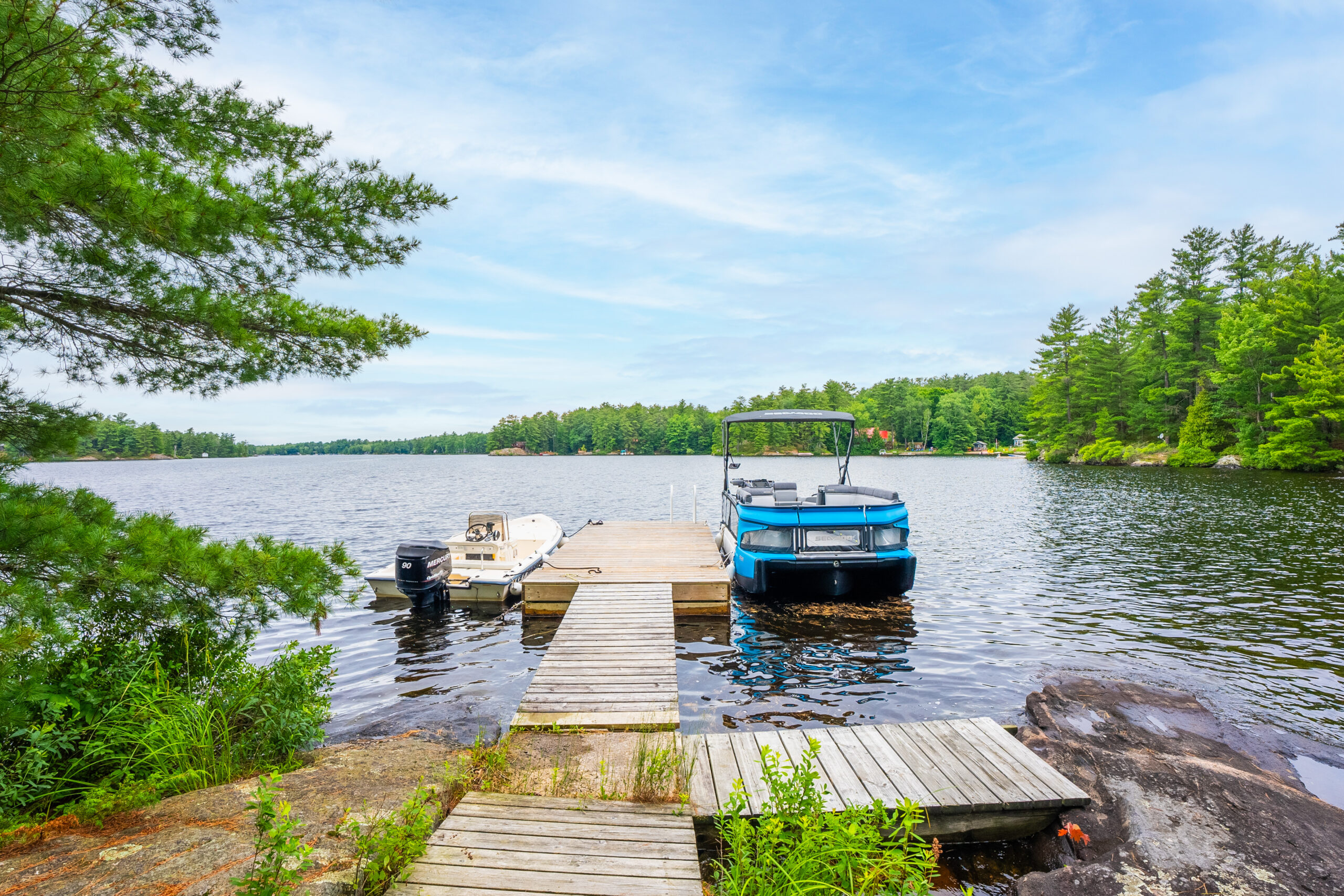 A dock goes out into the blue water with a blue boat parked at the end