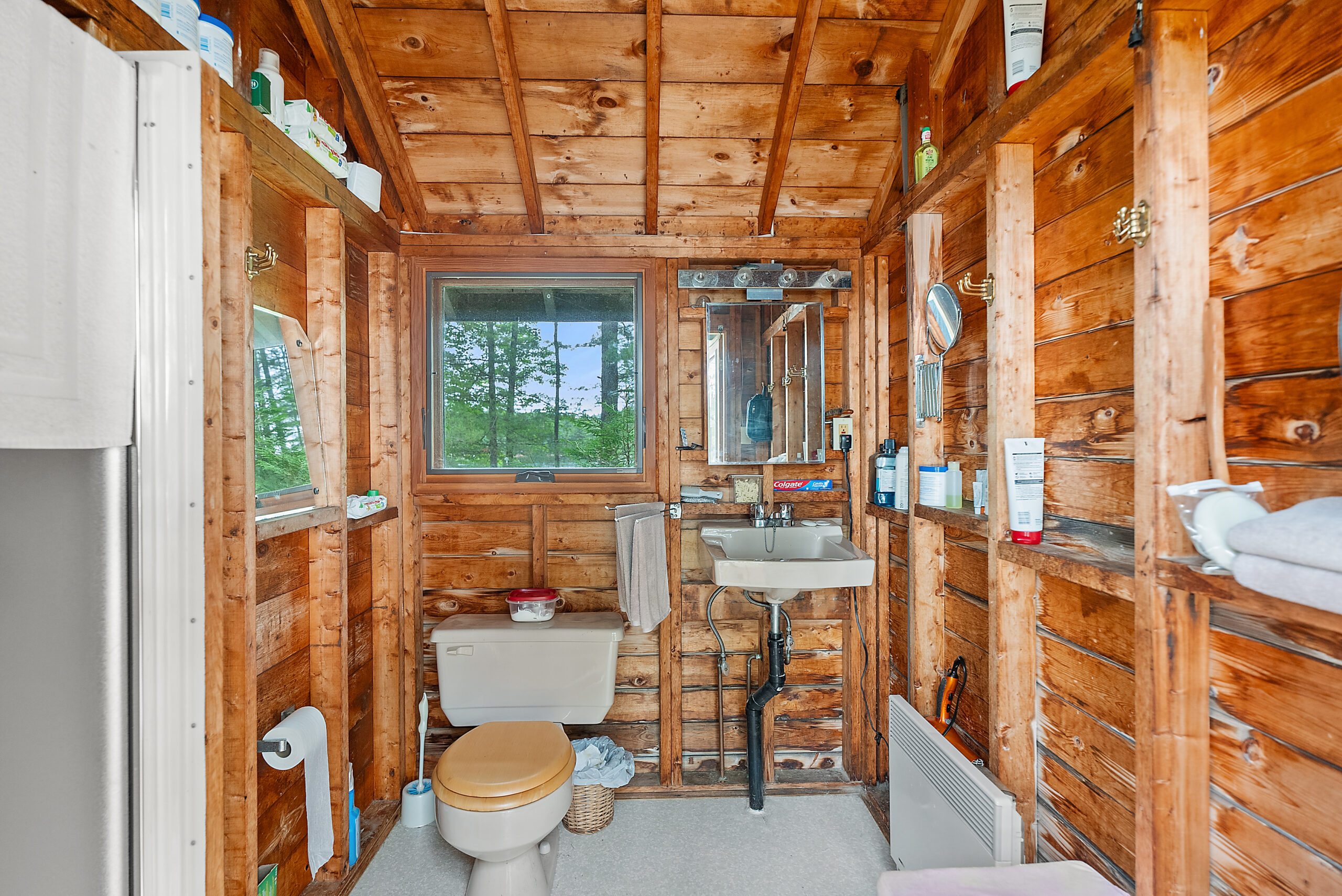 A toilet next to a small sink in a wood room