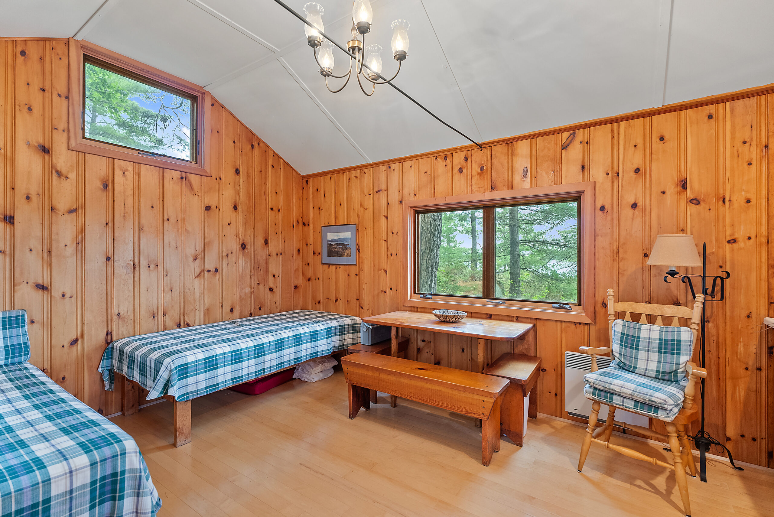 A blue plaid covered bed next to a wood picnic table in a red wood room