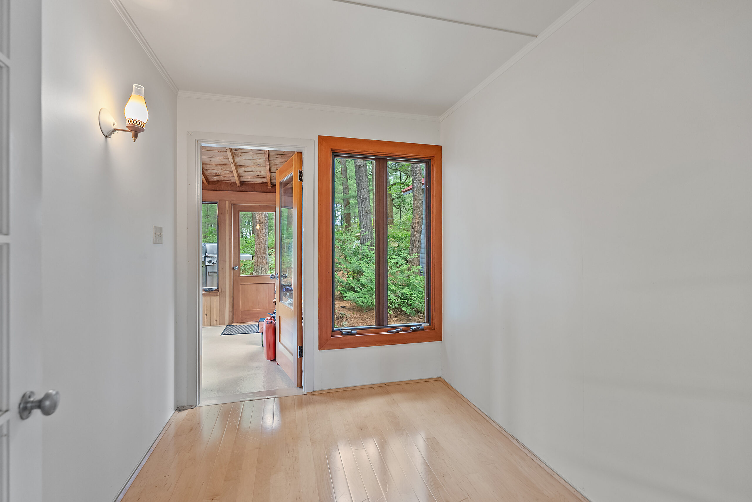 An open white room with a doorway into the sunroom