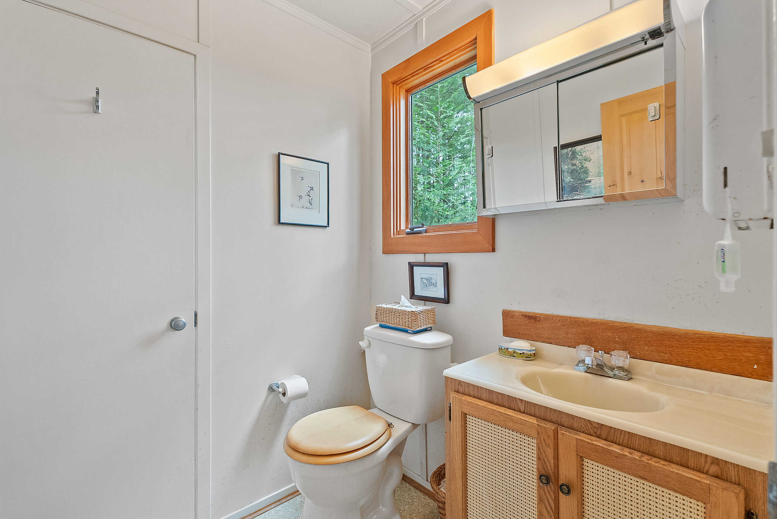 A white bathroom with a toilet and a wood vanity