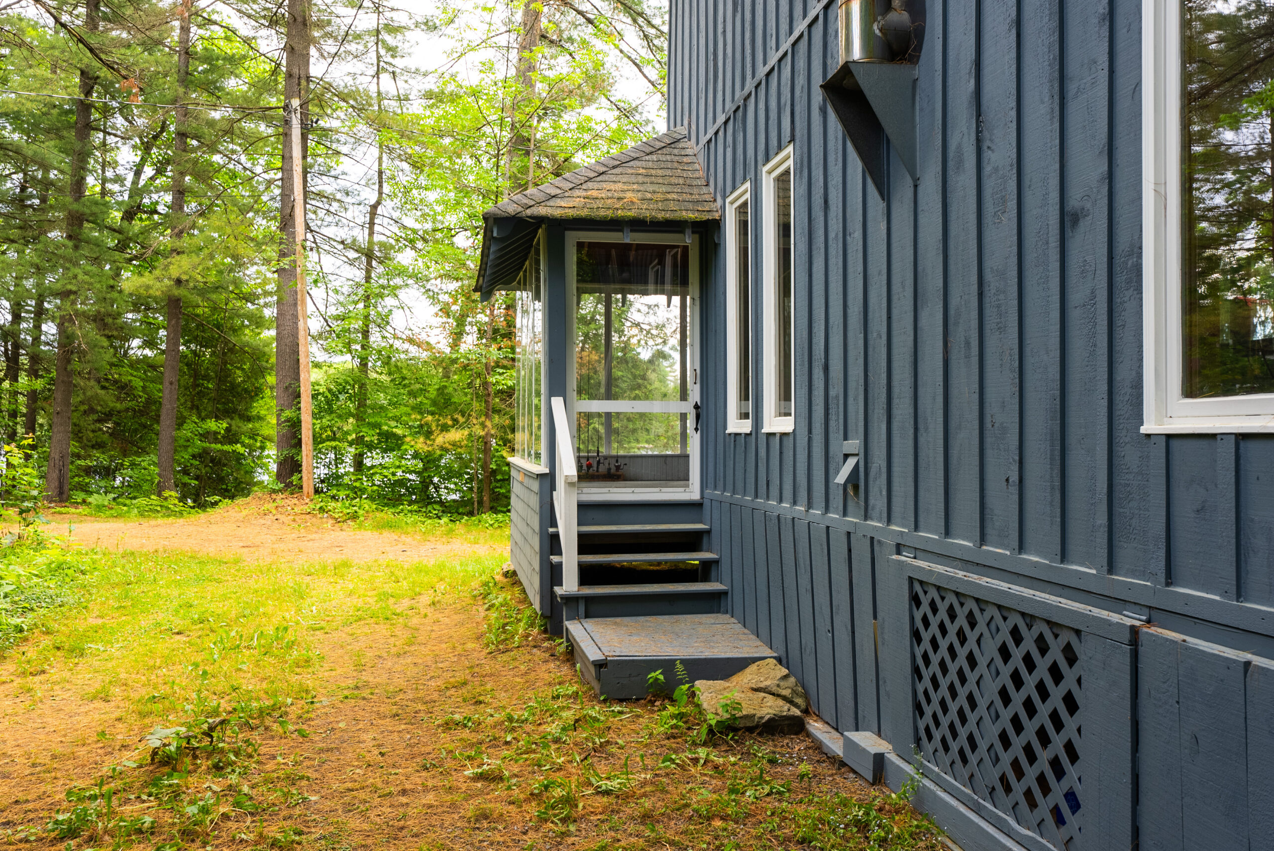 A small covered stairwell and door on the outside of the blue panelled cottage
