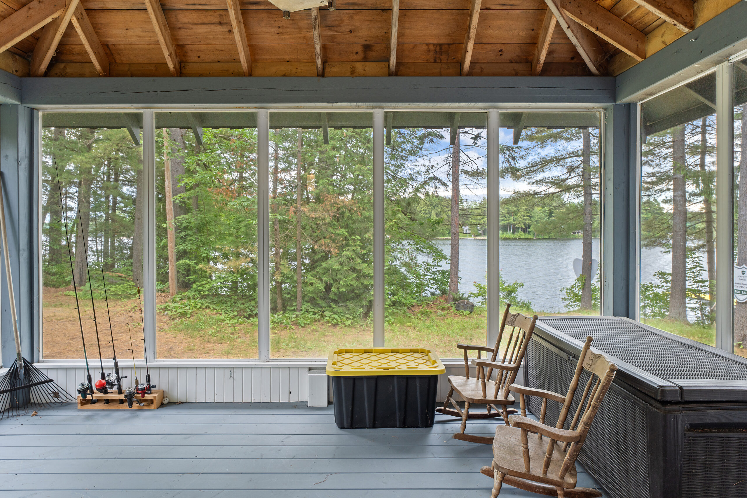 Floor-to-wall windows in an empty room have tree and lake views