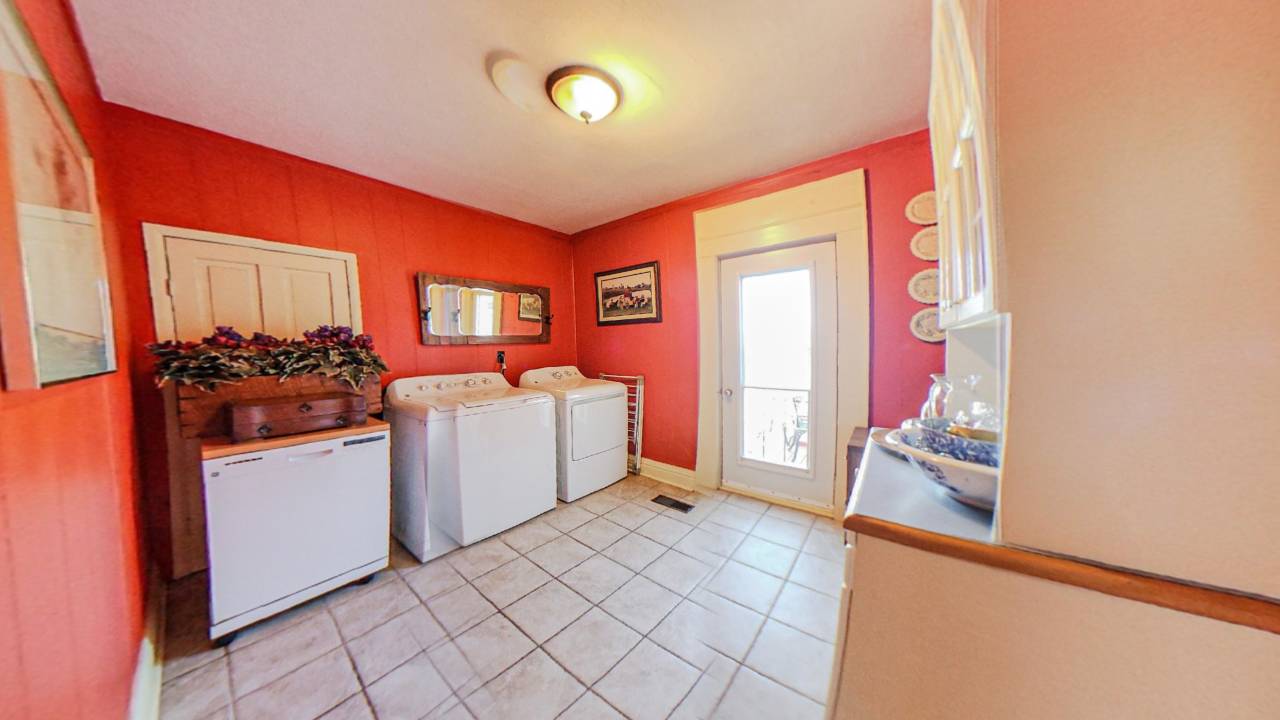 A red room with white tiles. White laundry machines next to a bright door