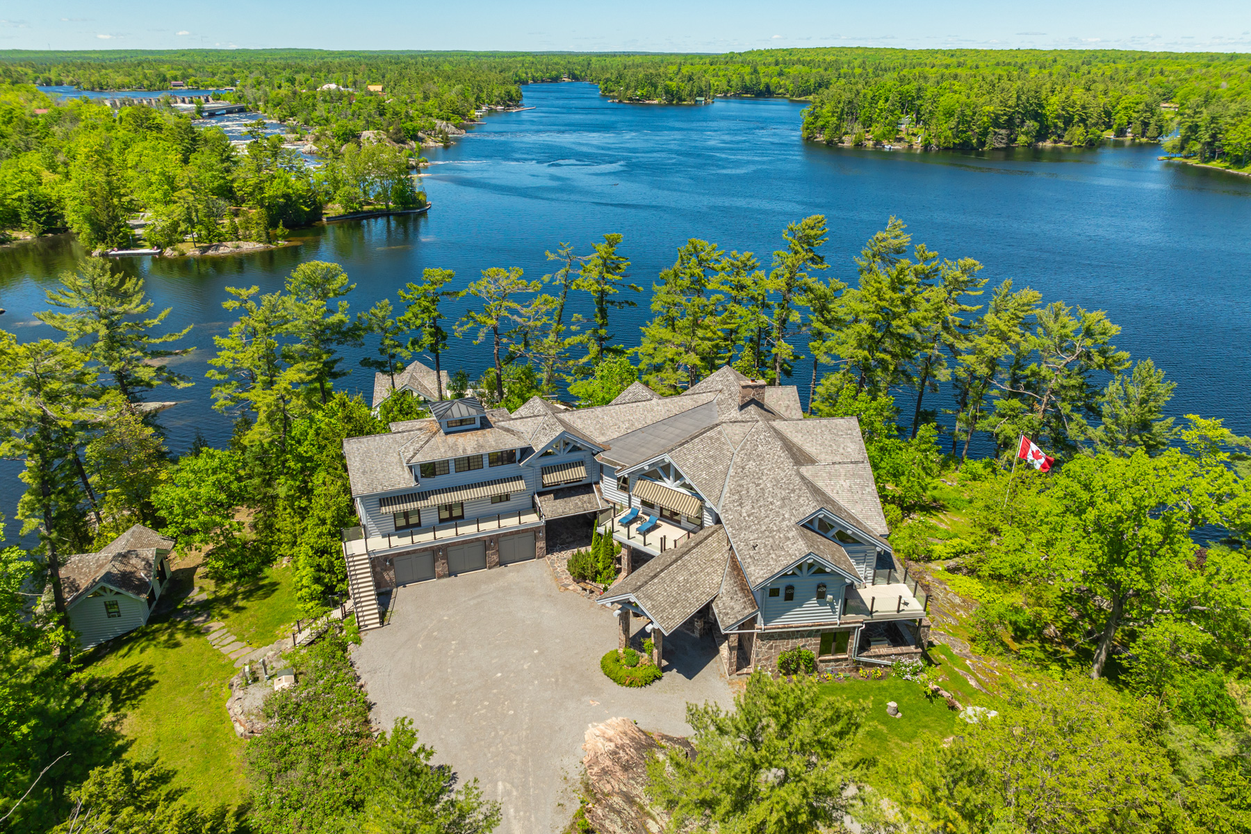 A large house with a big driveway on a lush green island with water behind
