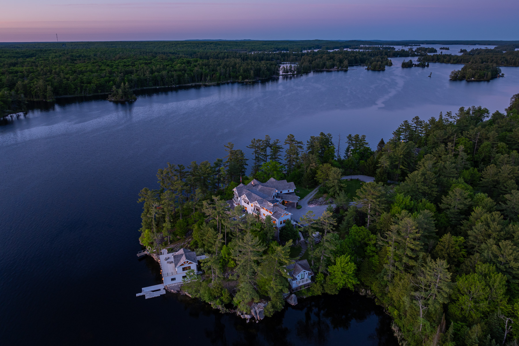 Aerial view of a large property surrounded by trees on the lake at night