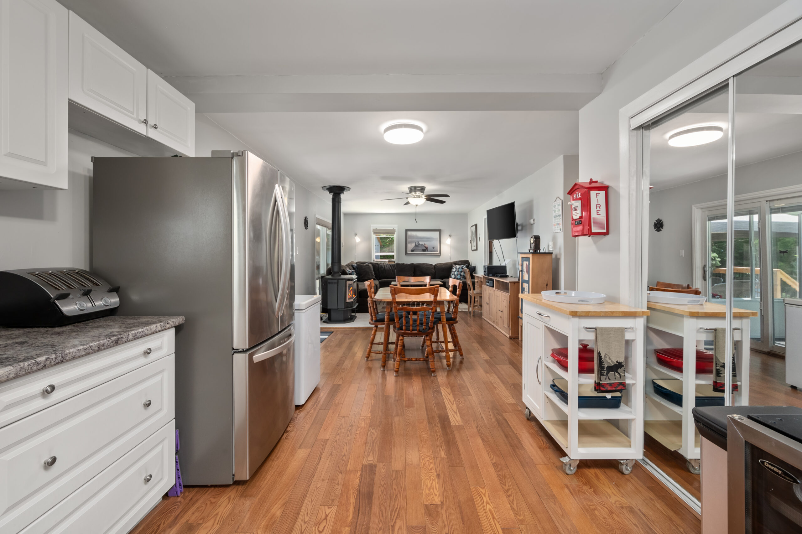 On the left, a white cabinet and a stainless steel fridge. In the centre, a dining table. To the right, a mirrored closet