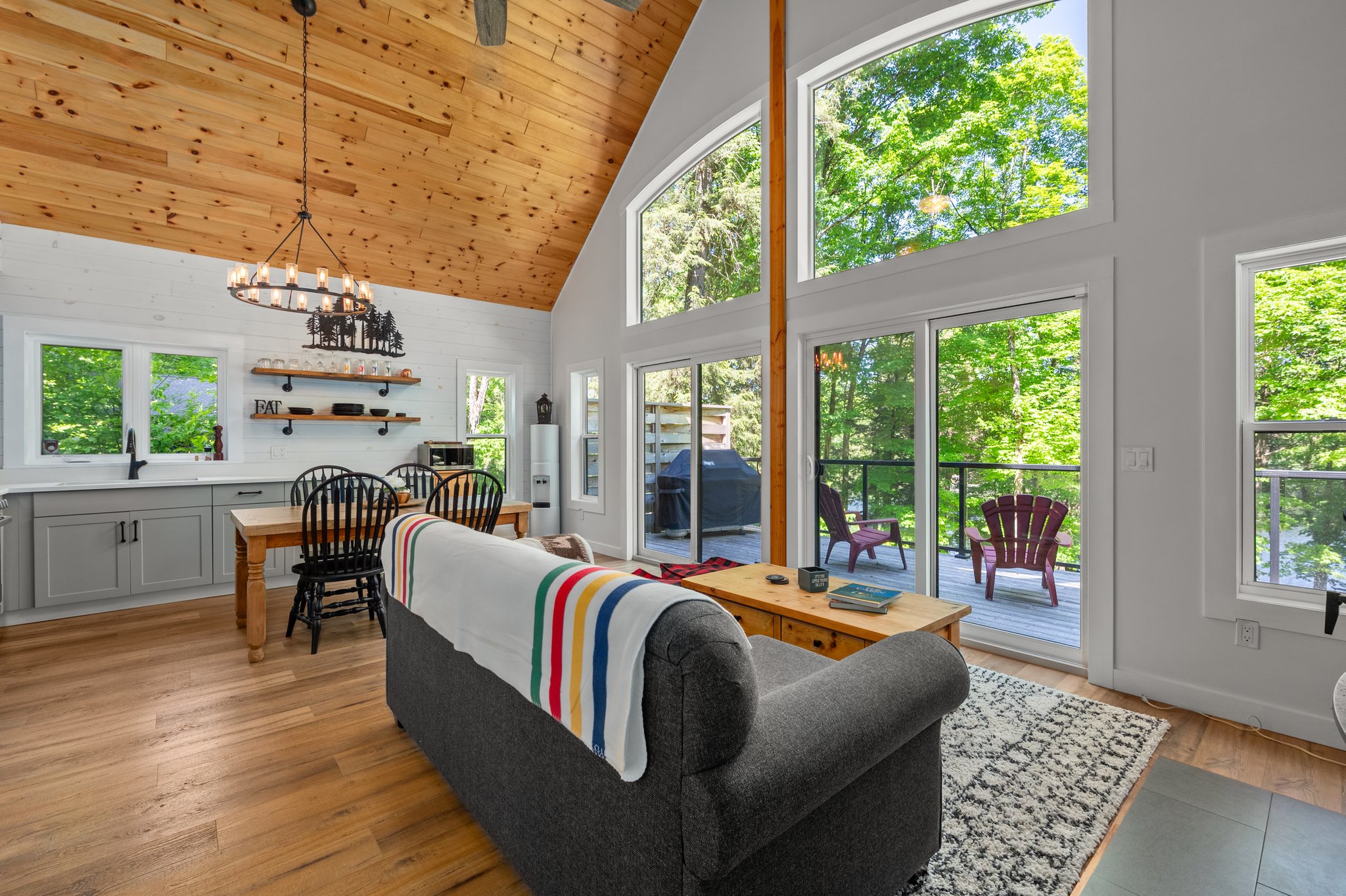 The back of a grey couch with a Hudson's Bay blanket hanging over it faces a wall of windows