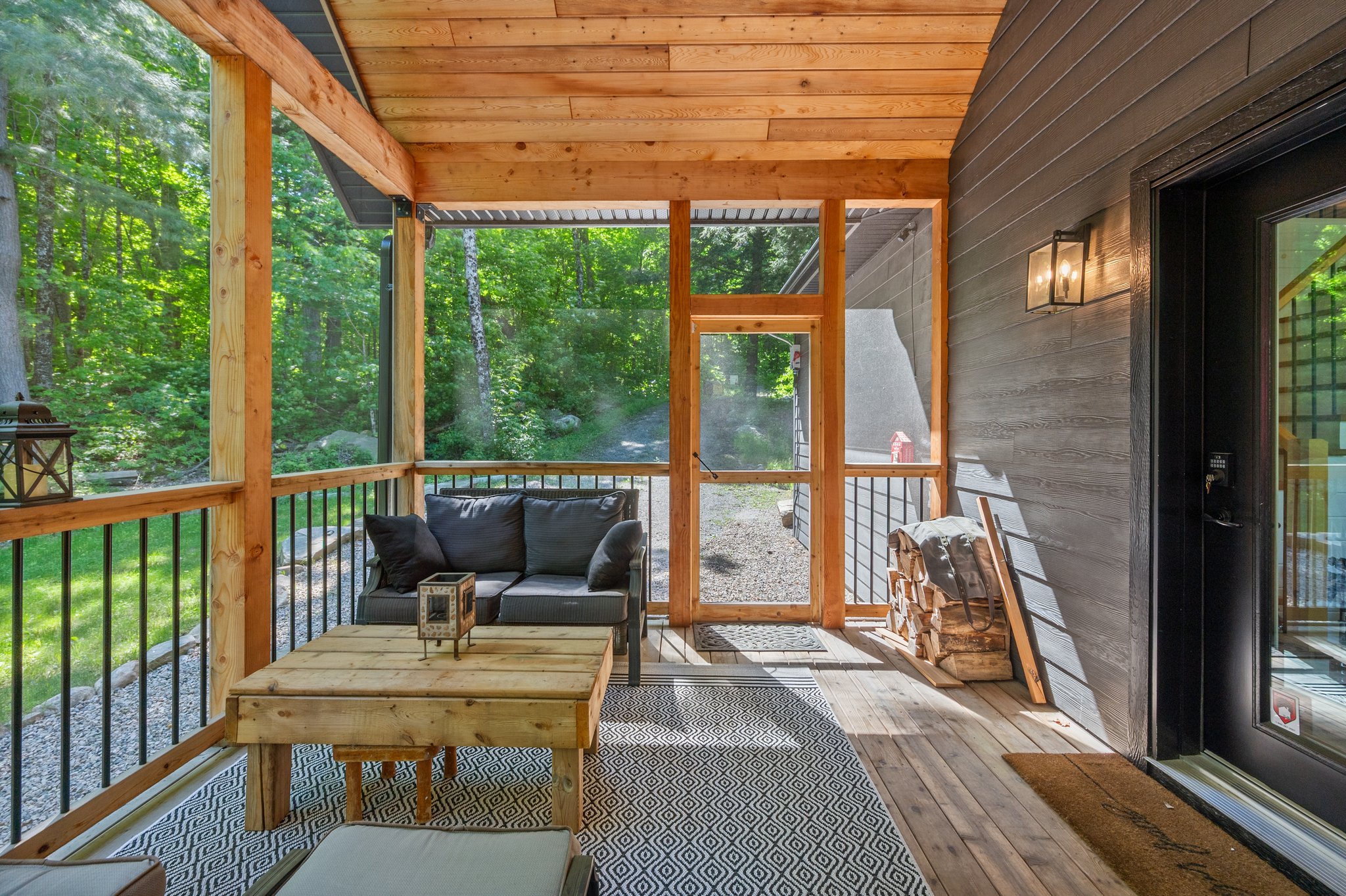 A small wood table and a grey loveseat in a screen-in room