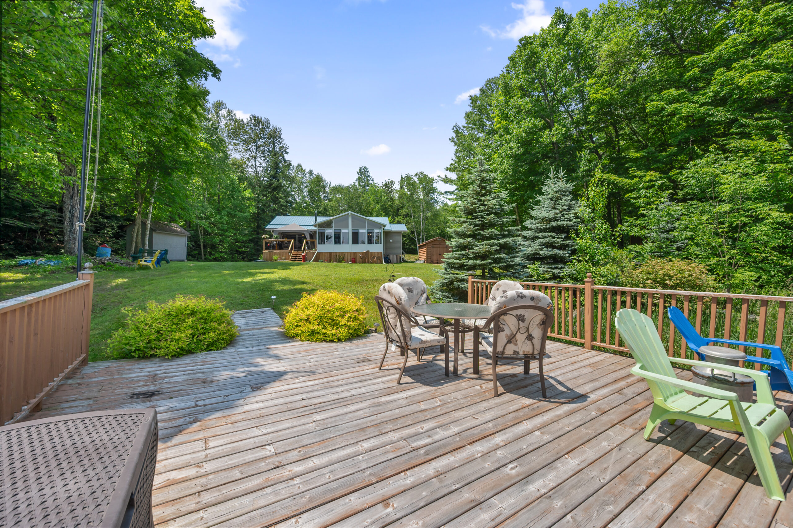 The wooden lakeside deck with seating faces the cottage