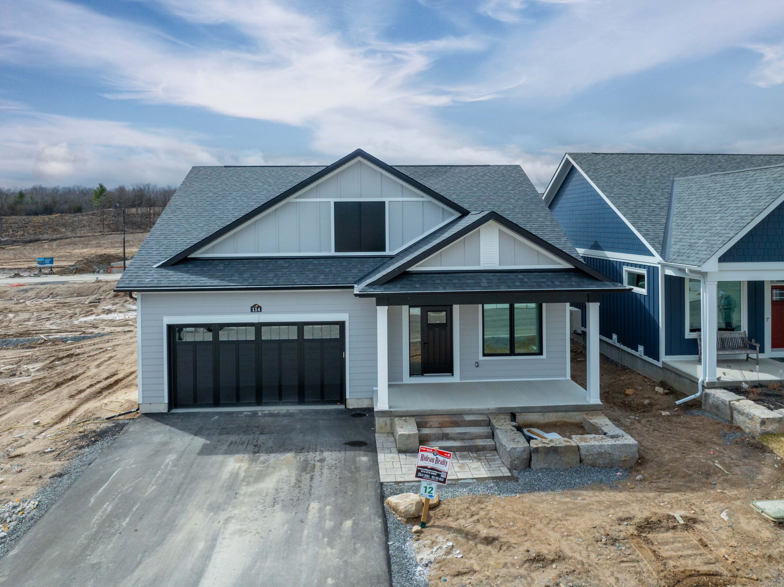 A grey panelled cottage on an unfinished lot
