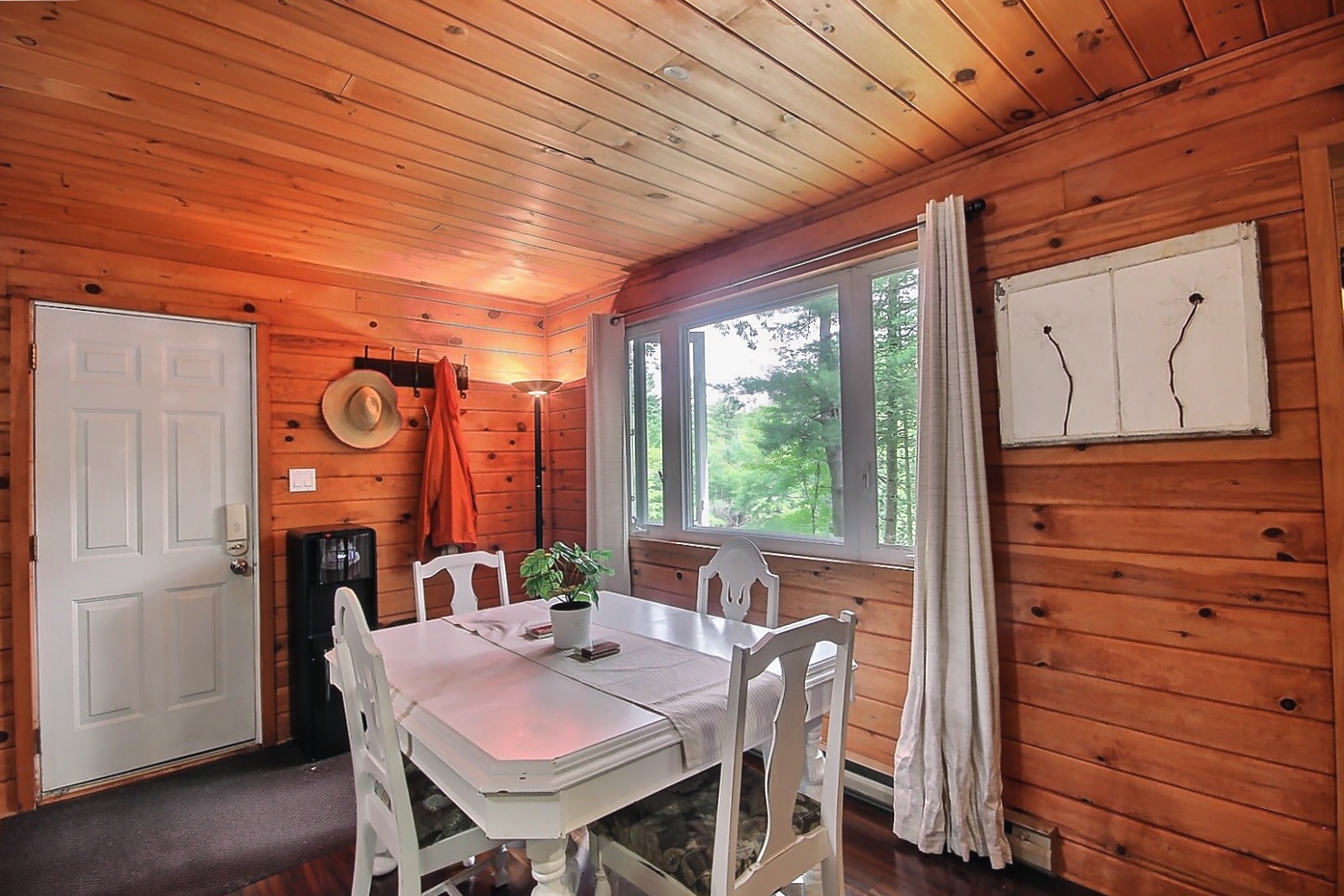 A small white dining table beside a large window with white curtains