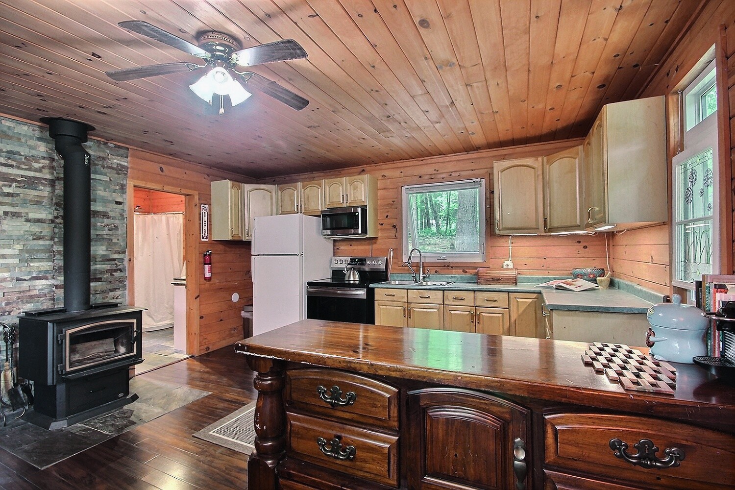 A kitchen along a wood panelled wall faces a dining table
