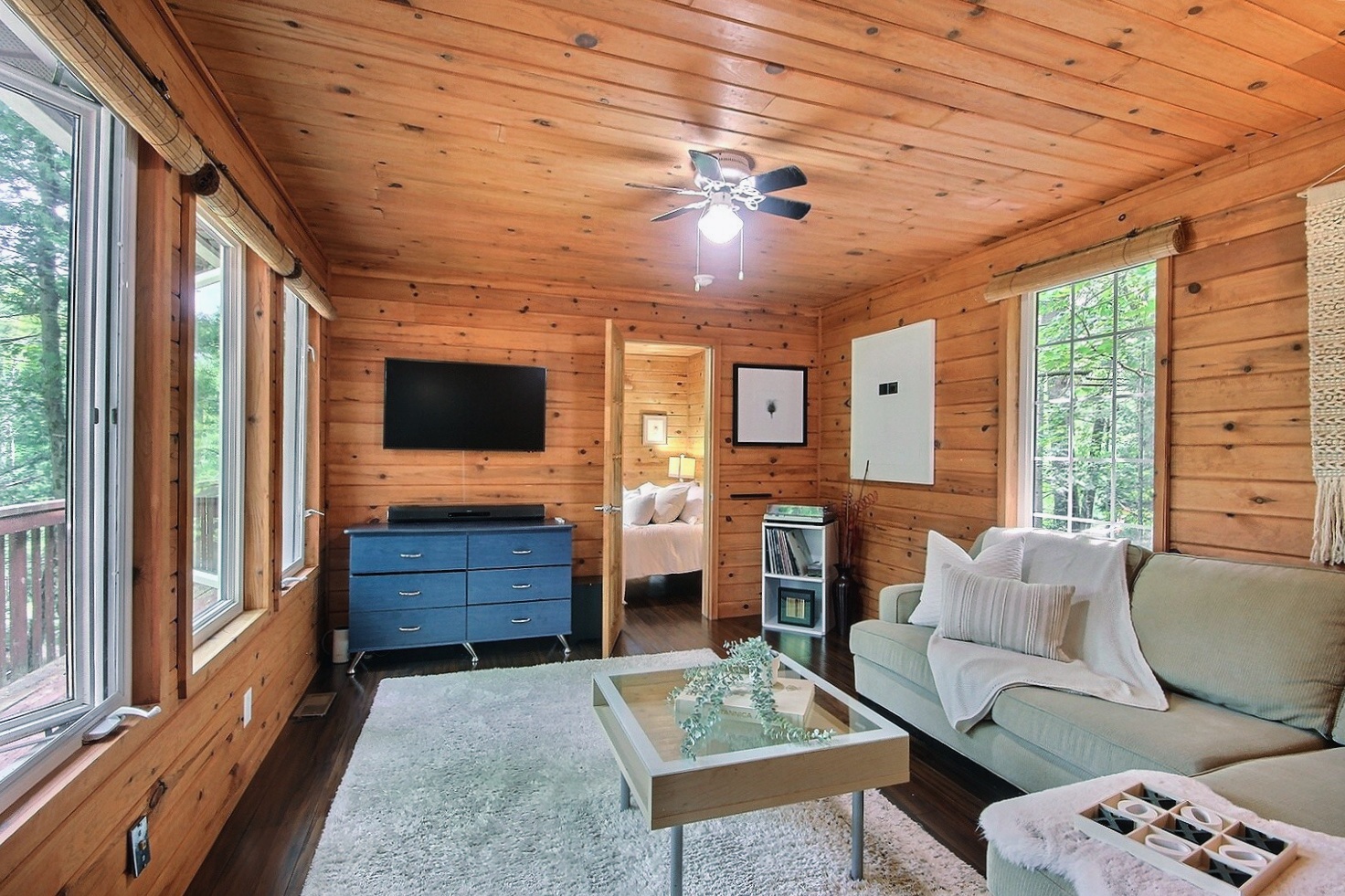 In a wood panelled room, a white couch faces a large window
